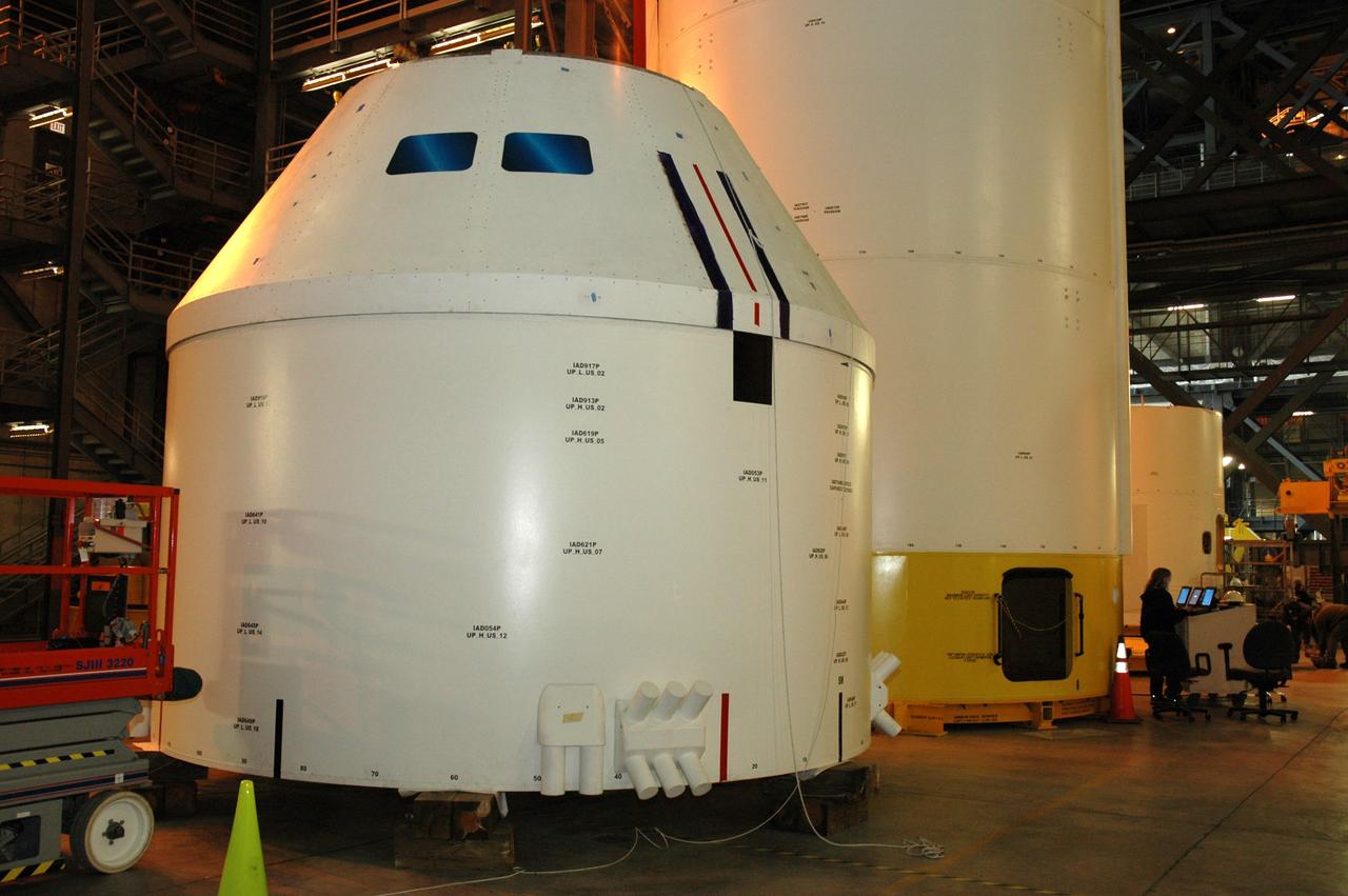 CAPE CANAVERAL, Fla. – In high bay 4 of the Vehicle Assembly Building at NASA's Kennedy Space Center in Florida, the Ares I-X crew/service module simulator (foreground) is being moved following a fit check.  Ares I-X is the test flight for the Ares I.   The I-X flight will provide NASA an early opportunity to test and prove hardware, facilities and ground operations associated with Ares I. The launch of the 327-foot-tall, full-scale Ares I-X, targeted for July 2009, will be the first in a series of unpiloted rocket launches from Kennedy. When fully developed, the 16-foot diameter crew module will furnish living space and reentry protection for the astronauts.  Photo credit: NASA/Tim Jacobs