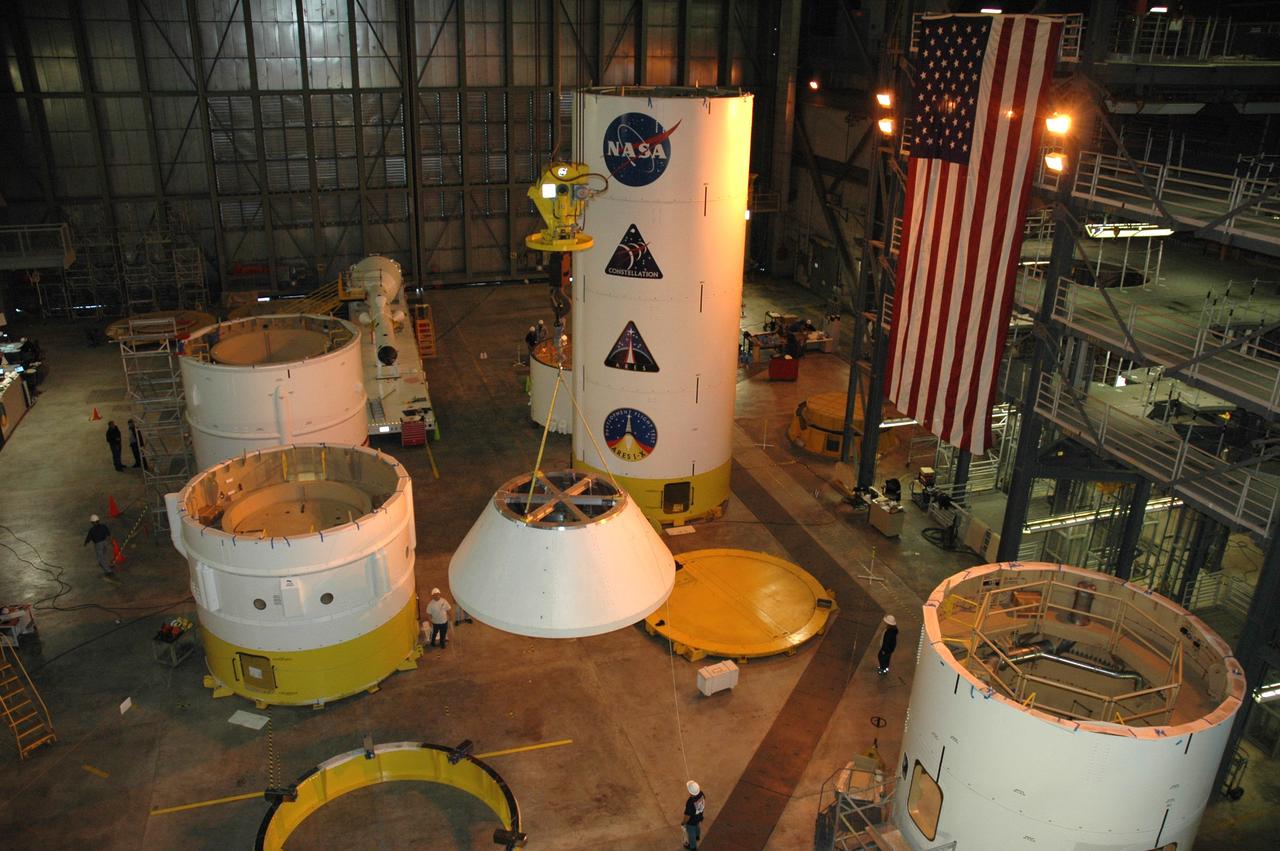 CAPE CANAVERAL, Fla. – In high bay 4 of the Vehicle Assembly Building at NASA's Kennedy Space Center in Florida, a crane moves the Ares I-X crew module simulator toward a stand at right.  Other Ares I-X segments are stacked around the floor of the bay.  Ares I-X is the test flight for the Ares I.   The I-X flight will provide NASA an early opportunity to test and prove hardware, facilities and ground operations associated with Ares I. The launch of the 327-foot-tall, full-scale Ares I-X, targeted for July 2009, will be the first in a series of unpiloted rocket launches from Kennedy. When fully developed, the 16-foot diameter crew module will furnish living space and reentry protection for the astronauts.  Photo credit: NASA/Tim Jacobs