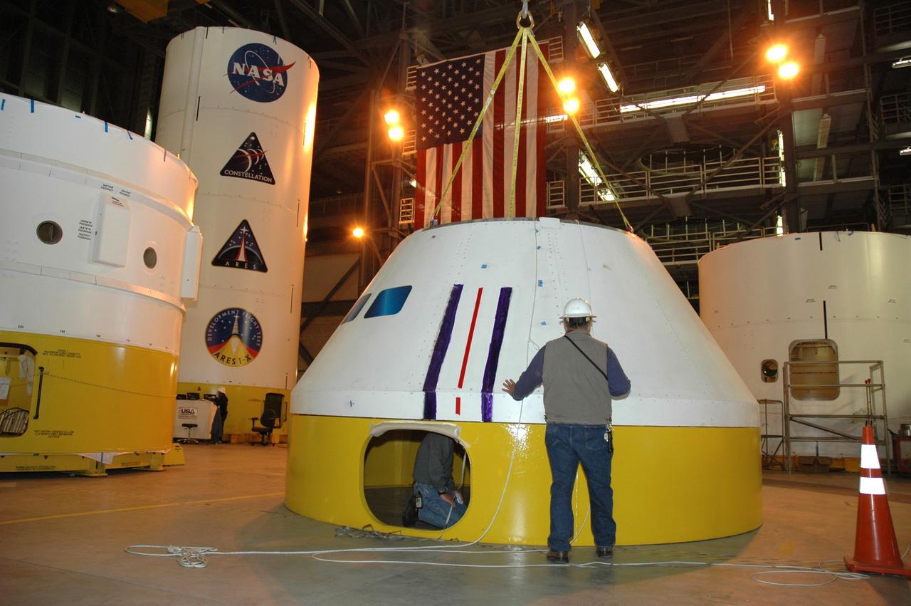 CAPE CANAVERAL, Fla. – In high bay 4 of the Vehicle Assembly Building at NASA's Kennedy Space Center in Florida, workers secure the Ares I-X crew module simulator onto its stand.  Ares I-X is the test flight for the Ares I.  The I-X flight will provide NASA an early opportunity to test and prove hardware, facilities and ground operations associated with Ares I. The launch of the 327-foot-tall, full-scale Ares I-X, targeted for July 2009, will be the first in a series of unpiloted rocket launches from Kennedy. When fully developed, the 16-foot diameter crew module will furnish living space and reentry protection for the astronauts.  Photo credit: NASA/Tim Jacobs