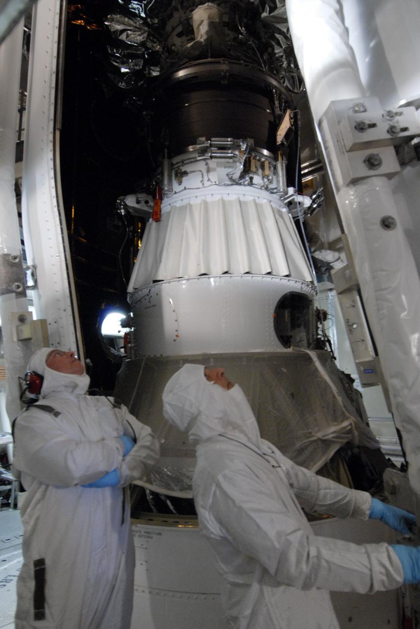 CAPE CANAVERAL, Fla. – On Launch Pad 17-B at Cape Canaveral Air Force Station in Florida, workers watch closely as the second half of the fairing moves toward NASA's Kepler spacecraft (left) to complete encapsulation. The fairing is a molded structure that fits flush with the outside surface of the rocket and forms an aerodynamically smooth nose cone, protecting the spacecraft during launch and ascent. The liftoff of Kepler aboard the Delta II rocket is currently targeted for launch in a window extending 10:49 to 10:52 p.m. EST March 6 from Pad 17-B. Kepler is designed to survey more than 100,000 stars in our galaxy to determine the number of sun-like stars that have Earth-size and larger planets, including those that lie in a star's "habitable zone," a region where liquid water, and perhaps life, could exist. If these Earth-size worlds do exist around stars like our sun, Kepler is expected to be the first to find them and the first to measure how common they are.  Photo credit: NASA/Jack Pfaller
