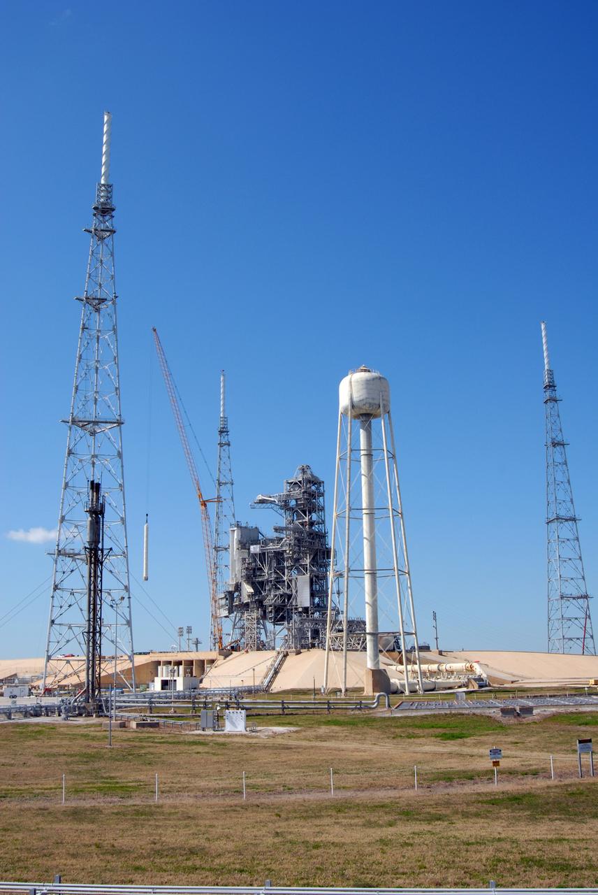 CAPE CANAVERAL, Fla. – On Launch Pad 39B at NASA's Kennedy Space Center in Florida, a crane has removed the 80-foot lightning mast from the top of the fixed service structure. The mast is no longer needed with the erection of the three lightning towers around the pad.  Pad 39B will be the site of the first Ares vehicle launch, including the Ares I-X test flight that is targeted for July 2009.  The three new lightning towers are 500 feet tall with an additional 100-foot fiberglass mast atop supporting a wire catenary system.  This improved lightning protection system allows for the taller height of the Ares I rocket compared to the space shuttle.  Photo credit: NASA/Amanda Diller