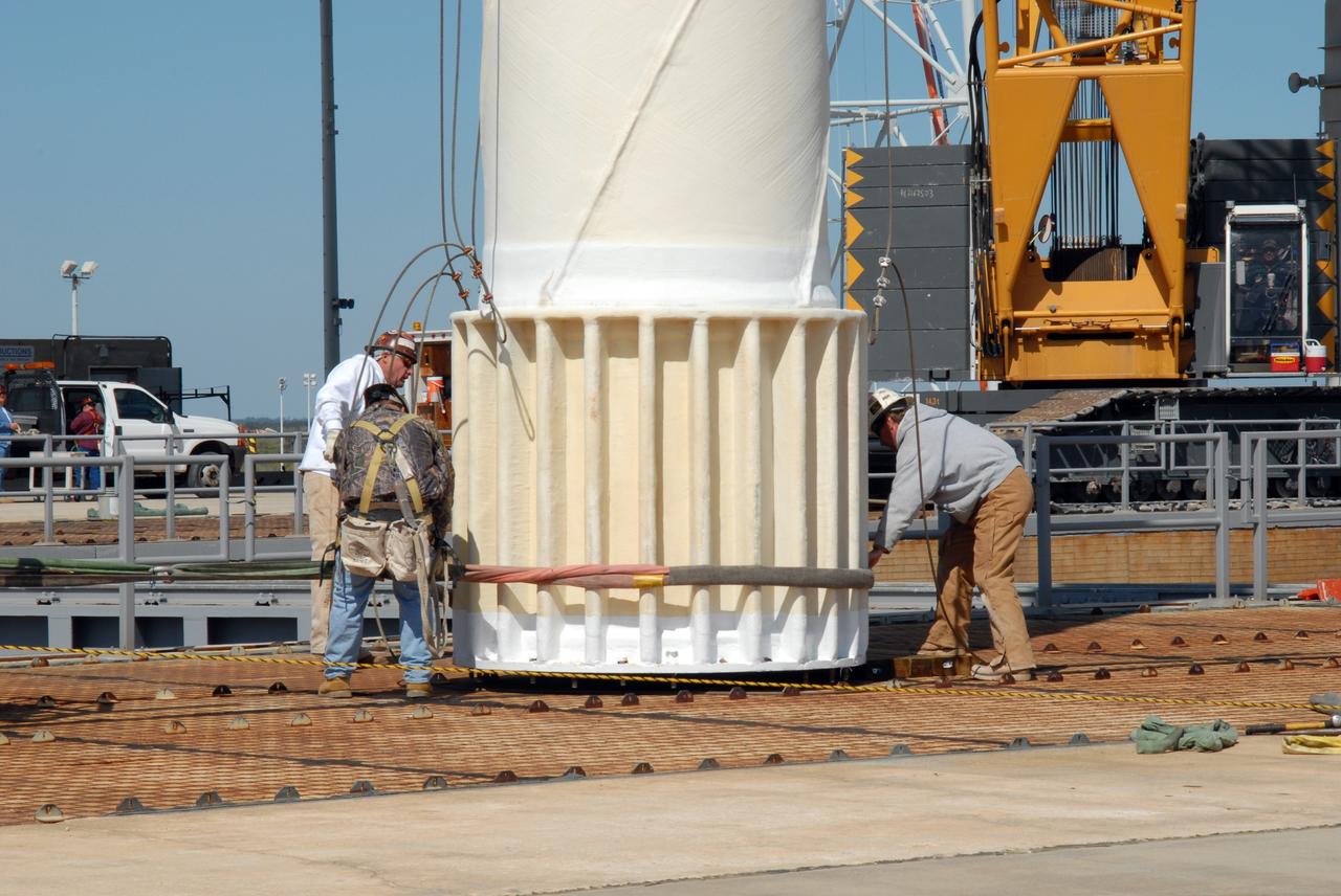 CAPE CANAVERAL, Fla. – On Launch Pad 39B at NASA's Kennedy Space Center in Florida, workers attach more cables to the 80-foot lightning mast removed from the top of the fixed service structure.  The mast will be lowered to horizontal for transport from the pad.  The mast is no longer needed with the erection of the three lightning towers around the pad.  Pad 39B will be the site of the first Ares vehicle launch, including the Ares I-X test flight that is targeted for July 2009.  The three new lightning towers are 500 feet tall with an additional 100-foot fiberglass mast atop supporting a wire catenary system.  This improved lightning protection system allows for the taller height of the Ares I rocket compared to the space shuttle.  Photo credit: NASA/Amanda Diller