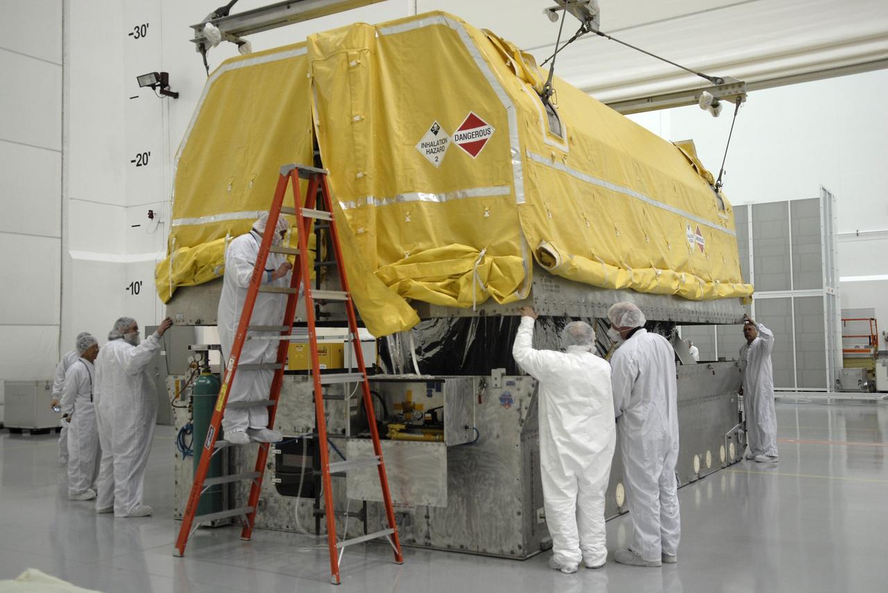 CAPE CANAVERAL, Fla. – In the Astrotech payload processing facility in Titusville, Fla., workers keep watch as the shipping container is lifted away from the Geostationary Operational Environmental Satellite, or GOES-O. The satellite will undergo final testing of the imaging system, instrumentation, communications and power systems.   Developed by NASA for the National Oceanic and Atmospheric Administration, or NOAA, the GOES-O satellite is targeted to launch April 28 onboard a United Launch Alliance Delta IV expendable launch vehicle.  Once in orbit, GOES-O will be designated GOES-14, and NASA will provide on-orbit checkout and then transfer operational responsibility to NOAA.  GOES-O will be placed in on-orbit storage as a replacement for an older GOES satellite.  Photo credit: NASA/Kim Shiflett