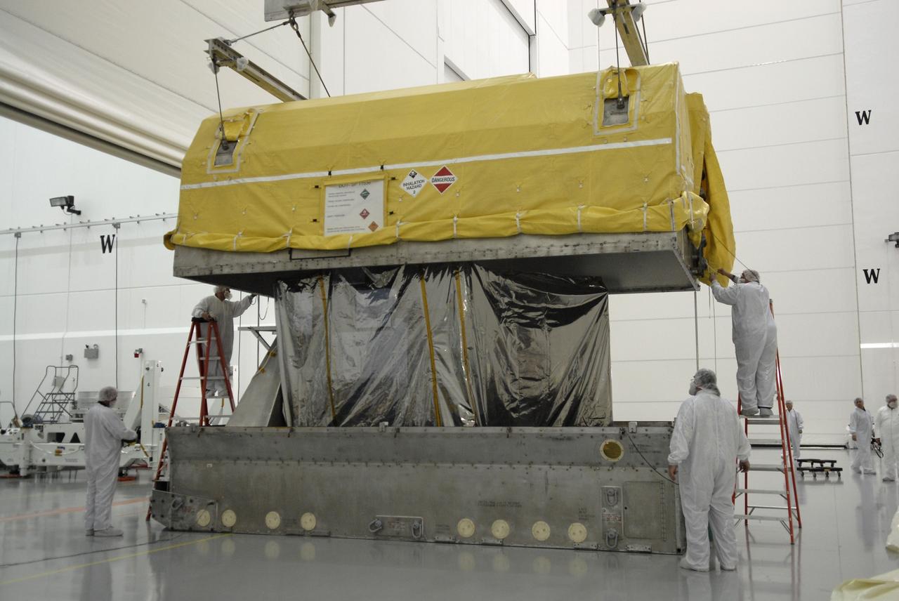 CAPE CANAVERAL, Fla. – In the Astrotech payload processing facility in Titusville, Fla., workers keep watch as the shipping container is lifted away from the Geostationary Operational Environmental Satellite, or GOES-O. The satellite will undergo final testing of the imaging system, instrumentation, communications and power systems.   Developed by NASA for the National Oceanic and Atmospheric Administration, or NOAA, the GOES-O satellite is targeted to launch April 28 onboard a United Launch Alliance Delta IV expendable launch vehicle.  Once in orbit, GOES-O will be designated GOES-14, and NASA will provide on-orbit checkout and then transfer operational responsibility to NOAA.  GOES-O will be placed in on-orbit storage as a replacement for an older GOES satellite.  Photo credit: NASA/Kim Shiflett