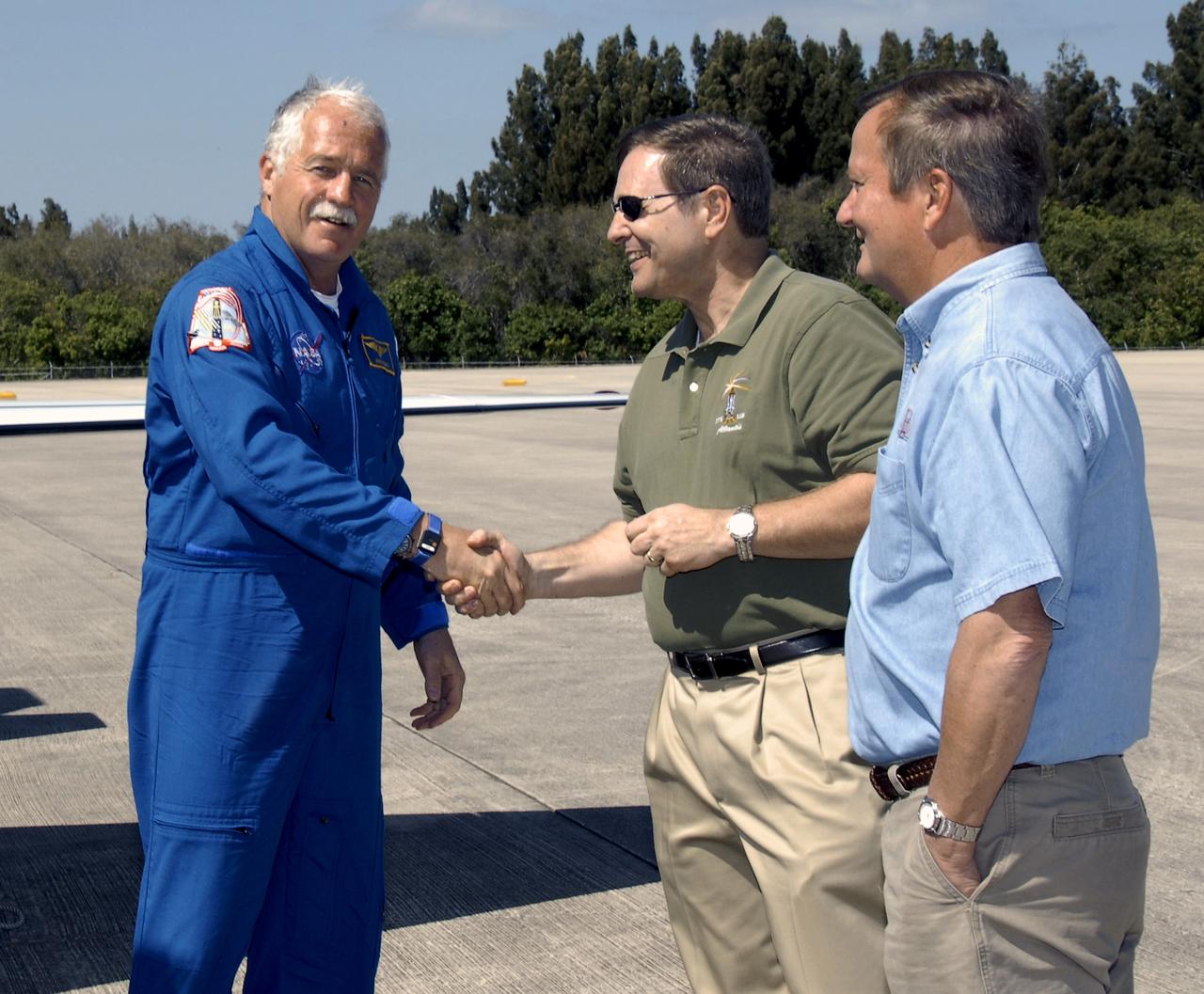 CAPE CANAVERAL, Fla. – The first crew members for space shuttle Discovery's STS-119 mission arrive at NASA's Kennedy Space Center in Florida to prepare for launch. From left, Mission Specialist John Phillips is greeted by Mike Wetmore, associate director for Engineering and Technical Operations at Kennedy, and Mike Leinbach, shuttle launch director. STS-119 is the 125th space shuttle flight and the 28th flight to the International Space Station. Discovery and its crew will deliver the final set of large power-generating solar array wings and integrated truss structure, S6, to the space station. The mission includes four spacewalks. Launch is scheduled for March 11 at 9:20 p.m. EDT. Photo credit: NASA/Kim Shiflett