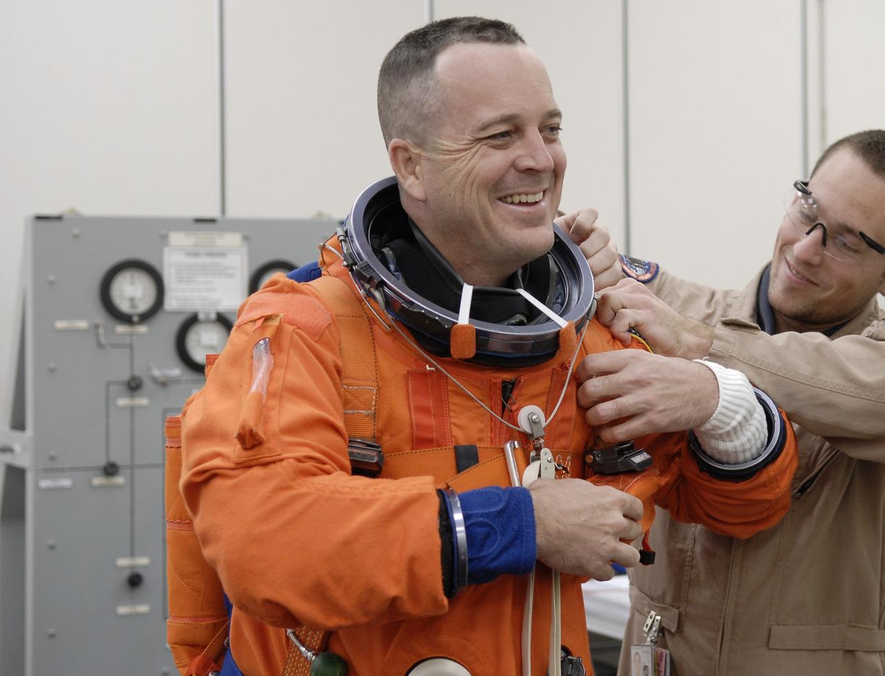 CAPE CANAVERAL, Fla. – In the Operations and Checkout Building at NASA's Kennedy Space Center in Florida, STS-119 Mission Specialist Richard Arnold gets help from a suit technician in the final fitting of his launch and entry suit. Arnold will be making his first shuttle flight. The 14-day mission is the 28th to the International Space Station and the 125th space shuttle flight.  Discovery will deliver the final pair of power-generating solar array wings and the S6 truss segment.  Installation of S6 will signal the station's readiness to house a six-member crew for conducting increased science.  Liftoff of Discovery is scheduled for 9:20 p.m. EDT on March 11.   Photo credit: NASA/Kim Shiflett
