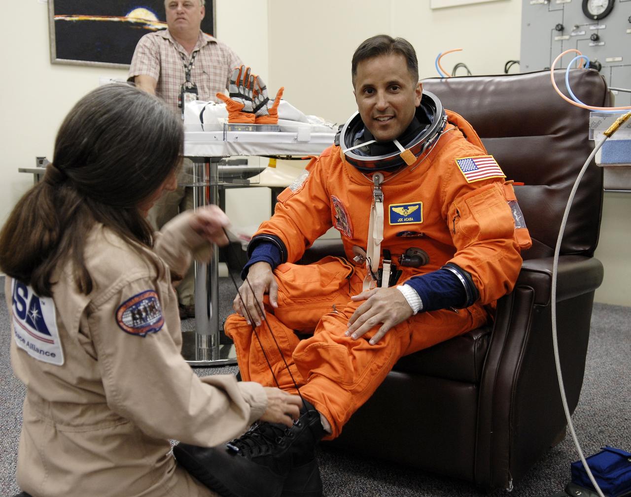 CAPE CANAVERAL, Fla. –  In the Operations and Checkout Building at NASA's Kennedy Space Center in Florida, STS-119 Mission Specialist Joseph Acaba is helped putting on his boots with his launch-and-entry suit. The crew will be heading for Launch Pad 39A and liftoff of space shuttle Discovery, scheduled for 7:43 p.m. EDT on March 15.  An earlier launch attempt March 11 was scrubbed at 2:36 p.m. due to a gaseous hydrogen leak from the external tank at the Ground Umbilical Carrier Plate during tanking. A seven-inch quick disconnect and two seals were replaced. The STS-119 mission is the 28th to the International Space Station and the 125th space shuttle flight.  Discovery will deliver the final pair of power-generating solar array wings and the S6 truss segment.  Installation of S6 will signal the station's readiness to house a six-member crew for conducting increased science.  Photo credit: NASA/Kim Shiflett