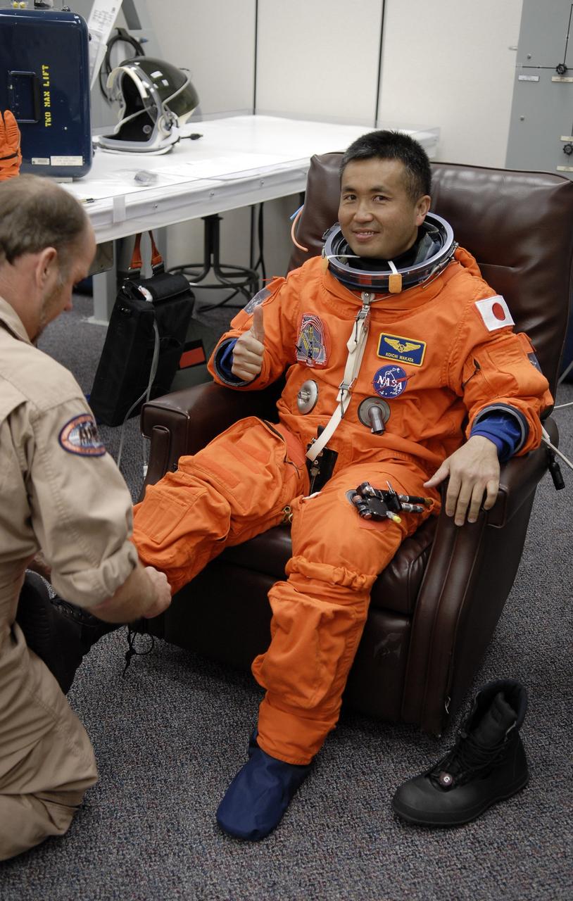 CAPE CANAVERAL, Fla. – In the Operations and Checkout Building at NASA's Kennedy Space Center in Florida, STS-119 Mission Specialist Koichi Wakata is helped with his boots as he puts on his launch-and-entry suit.  The crew will be heading for Launch Pad 39A and liftoff of space shuttle Discovery, scheduled for 7:43 p.m. EDT on March 15.  An earlier launch attempt March 11 was scrubbed at 2:36 p.m. due to a gaseous hydrogen leak from the external tank at the Ground Umbilical Carrier Plate during tanking. A seven-inch quick disconnect and two seals were replaced. The STS-119 mission is the 28th to the International Space Station and the 125th space shuttle flight.  Discovery will deliver the final pair of power-generating solar array wings and the S6 truss segment.  Installation of S6 will signal the station's readiness to house a six-member crew for conducting increased science.  Photo credit: NASA/Kim Shiflett