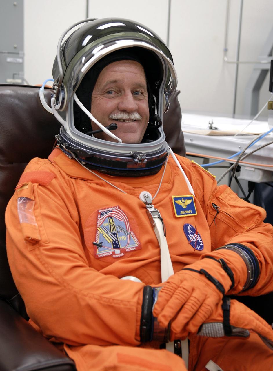 CAPE CANAVERAL, Fla. – In the Operations and Checkout Building at NASA's Kennedy Space Center in Florida, STS-119 Mission Specialist John Phillips  completes putting on his launch-and-entry suit, including the helmet, for the launch of space shuttle Discovery.  The crew will be heading for Launch Pad 39A and liftoff of Discovery, scheduled for 7:43 p.m. EDT on March 15. An earlier launch attempt March 11 was scrubbed at 2:36 p.m. due to a gaseous hydrogen leak from the external tank at the Ground Umbilical Carrier Plate during tanking. A seven-inch quick disconnect and two seals were replaced. The STS-119 mission is the 28th to the International Space Station and the 125th space shuttle flight.  Discovery will deliver the final pair of power-generating solar array wings and the S6 truss segment.  Installation of S6 will signal the station's readiness to house a six-member crew for conducting increased science.  Photo credit: NASA/Kim Shiflett