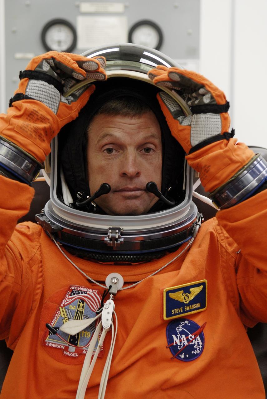 CAPE CANAVERAL, Fla. – In the Operations and Checkout Building at NASA's Kennedy Space Center in Florida, STS-119 Mission Specialist Steve Swanson adjusts his helmet as he puts on the launch-and-entry suit for the launch of space shuttle Discovery.  The crew will be heading for Launch Pad 39A and liftoff of Discovery, scheduled for 7:43 p.m. EDT on March 15. An earlier launch attempt March 11 was scrubbed at 2:36 p.m. due to a gaseous hydrogen leak from the external tank at the Ground Umbilical Carrier Plate during tanking. A seven-inch quick disconnect and two seals were replaced. The STS-119 mission is the 28th to the International Space Station and the 125th space shuttle flight.  Discovery will deliver the final pair of power-generating solar array wings and the S6 truss segment.  Installation of S6 will signal the station's readiness to house a six-member crew for conducting increased science.  Photo credit: NASA/Kim Shiflett