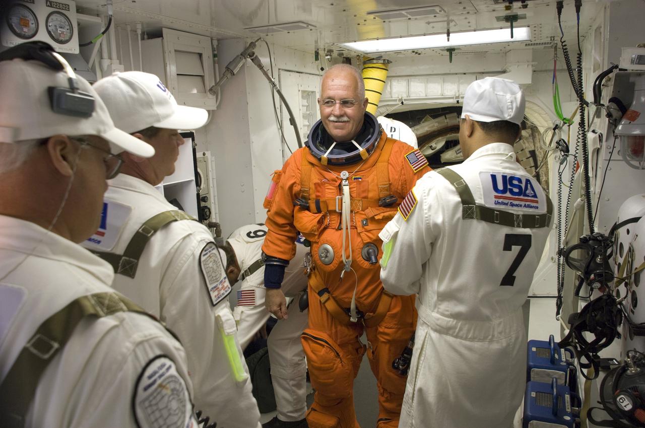 CAPE CANAVERAL, Fla. – In the White Room on Launch Pad 39A at NASA's Kennedy Space Center in Florida, STS-119 Mission Specialist John Phillips is helped by the closeout crew putting on his harness, which includes a parachute pack, before crawling through the open hatch into space shuttle Discovery. The White Room is at the end of the orbiter access arm on the fixed service structure and provides access into the shuttle. The STS-119 mission is the 28th to the International Space Station and the 125th space shuttle flight.  Discovery will deliver the final pair of power-generating solar array wings and the S6 truss segment.  Installation of S6 will signal the station's readiness to house a six-member crew for conducting increased science. Liftoff is scheduled for 7:43 p.m. EDT. Photo credit: NASA/Tony Gray, Tom Farrar