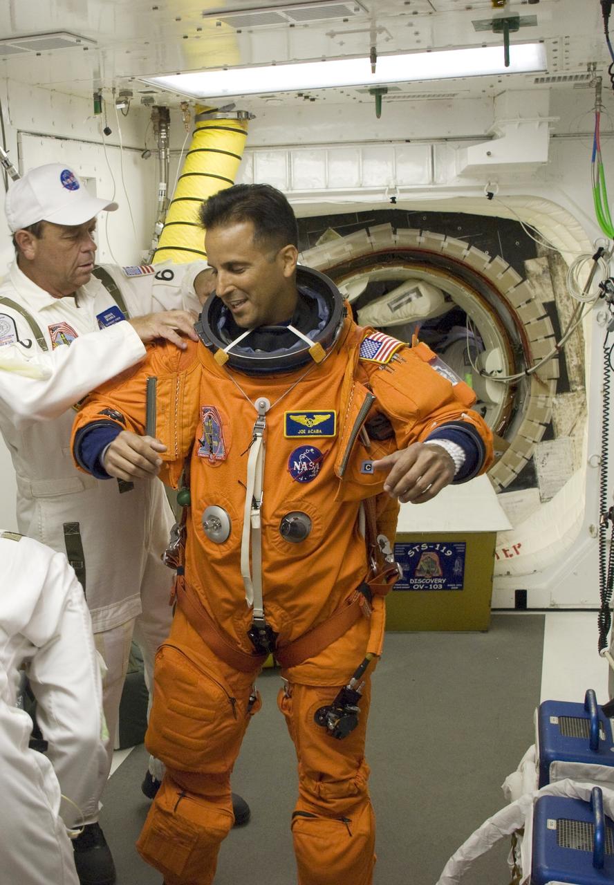 CAPE CANAVERAL, Fla. – In the White Room on Launch Pad 39A at NASA's Kennedy Space Center in Florida, STS-119 Mission Specialist Joseph Acaba is helped by the closeout crew putting on his harness, which includes a parachute pack, before crawling through the open hatch into space shuttle Discovery. The White Room is at the end of the orbiter access arm on the fixed service structure and provides access into the shuttle. The STS-119 mission is the 28th to the International Space Station and the 125th space shuttle flight.  Discovery will deliver the final pair of power-generating solar array wings and the S6 truss segment.  Installation of S6 will signal the station's readiness to house a six-member crew for conducting increased science. Liftoff is scheduled for 7:43 p.m. EDT. Photo credit: NASA/Tony Gray, Tom Farrar