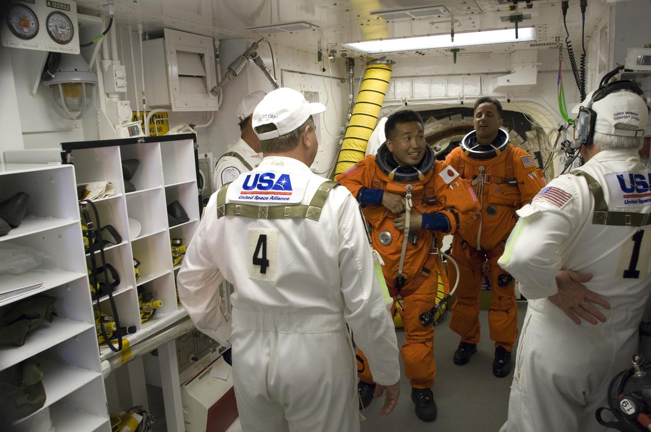 CAPE CANAVERAL, Fla. – In the White Room on Launch Pad 39A at NASA's Kennedy Space Center in Florida, STS-119 Mission Specialists Koichi Wakata (center) and Steve Swanson are getting into their harnesses, which include a parachute pack, before crawling through the open hatch into space shuttle Discovery. The White Room is at the end of the orbiter access arm on the fixed service structure and provides access into the shuttle. The STS-119 mission is the 28th to the International Space Station and the 125th space shuttle flight.  Discovery will deliver the final pair of power-generating solar array wings and the S6 truss segment.  Installation of S6 will signal the station's readiness to house a six-member crew for conducting increased science. Liftoff is scheduled for 7:43 p.m. EDT. Photo credit: NASA/Tony Gray, Tom Farrar