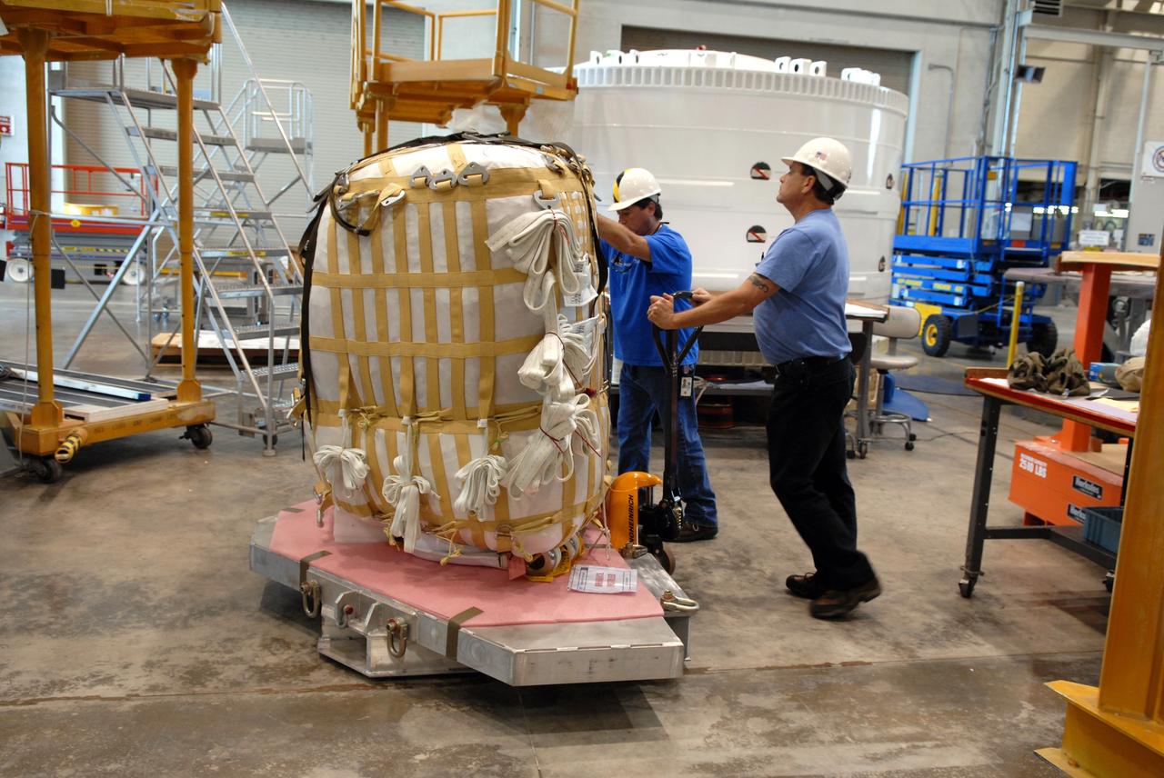 CAPE CANAVERAL, Fla. – In the Assembly and Refurbishment Facility at NASA's Kennedy Space Center in Florida, workers move a parachute pack for installation in the Ares I-X forward skirt segment. The forward skirt is the initial piece of first-stage hardware in preparation for the July 2009 test flight of the agency's next-generation spacecraft and launch vehicle system.  Photo credit: NASA/Jack Pfaller