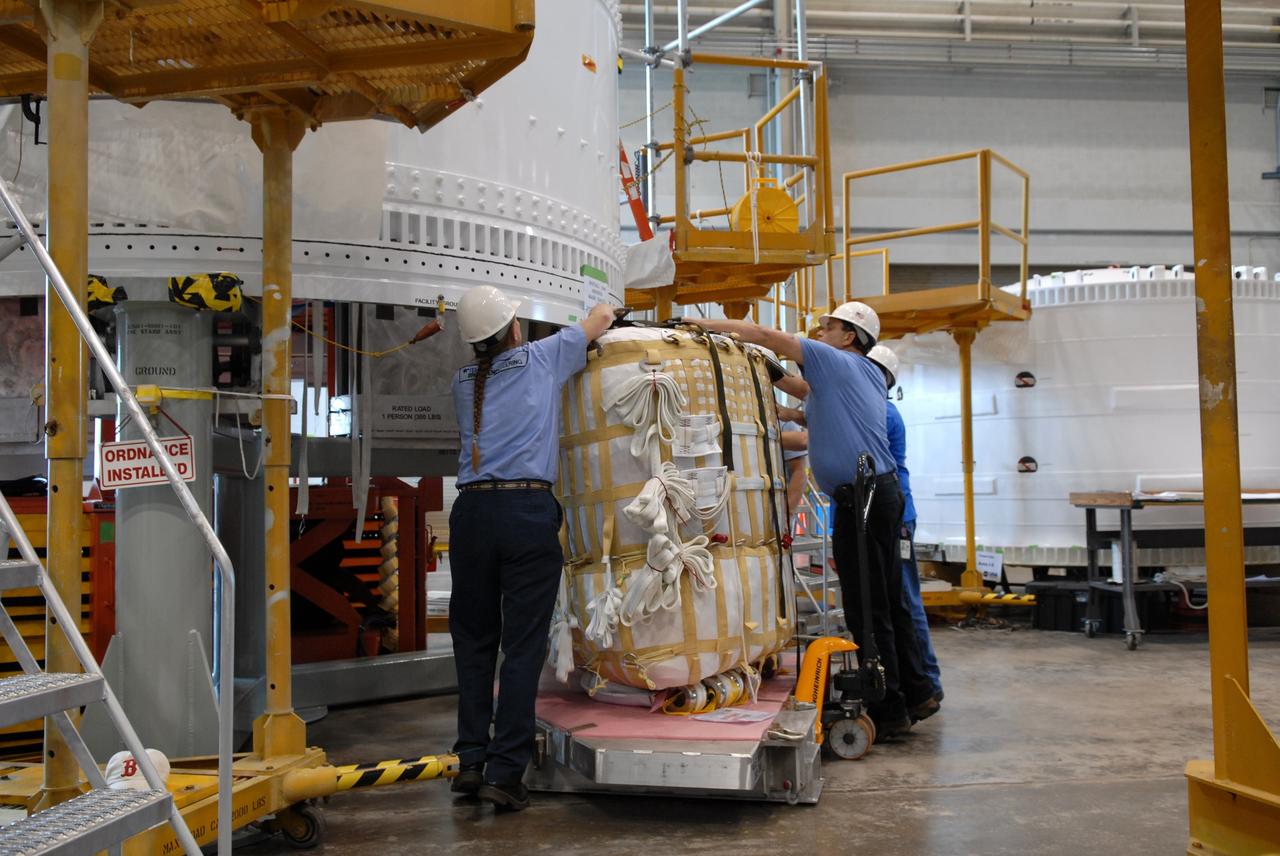 CAPE CANAVERAL, Fla. – In the Assembly and Refurbishment Facility at NASA's Kennedy Space Center in Florida, workers move a parachute pack to the Ares I-X forward skirt segment, in which it will be installed. The forward skirt is the initial piece of first-stage hardware in preparation for the July 2009 test flight of the agency's next-generation spacecraft and launch vehicle system.  Photo credit: NASA/Jack Pfaller