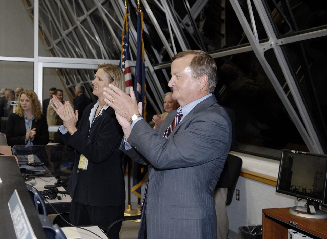 CAPE CANAVERAL, Fla. – In Firing Room 4 of the Launch Control Center at NASA's Kennedy Space Center in Florida, Flow Director for space shuttle Discovery Stephanie Stilson (center) and Shuttle Launch Director Mike Leinbach applaud the mission management team for the successful launch of space shuttle Discovery on the STS-119 mission. Launch was on time at 7:43 p.m. EDT. The STS-119 mission is the 28th to the space station and Discovery's 36th flight.  Discovery will deliver the final pair of power-generating solar array wings and the S6 truss segment.  Installation of S6 will signal the station's readiness to house a six-member crew for conducting increased science.  Photo credit: NASA/Kim Shiflett