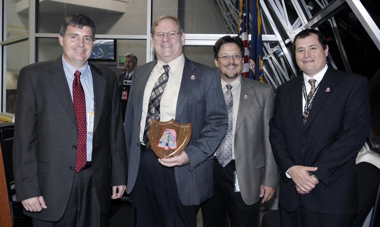 CAPE CANAVERAL, Fla. – In Firing Room 4 of the Launch Control Center at NASA's Kennedy Space Center in Florida,  from left, Steve Stich, manager of the Kennedy Orbiter Project Office;  John Fraser, with Boeing Co. at the Marshall Space Flight Center; Rick Russell, with the NASA Orbiter Sustaining Engineering Office; and Rene Ortega with Marshall Space Flight Center's Shuttle Propulsion Office, are presented with a plaque for their work on the fuel control valve problem on space shuttle Discovery. The award was presented after the successful launch of Discovery on the STS-119 mission.  Liftoff was on time at 7:43 p. m. EDT. The STS-119 mission is the 28th to the space station and Discovery's 36th flight.  Discovery will deliver the final pair of power-generating solar array wings and the S6 truss segment.  Installation of S6 will signal the station's readiness to house a six-member crew for conducting increased science.  Photo credit: NASA/Kim Shiflett