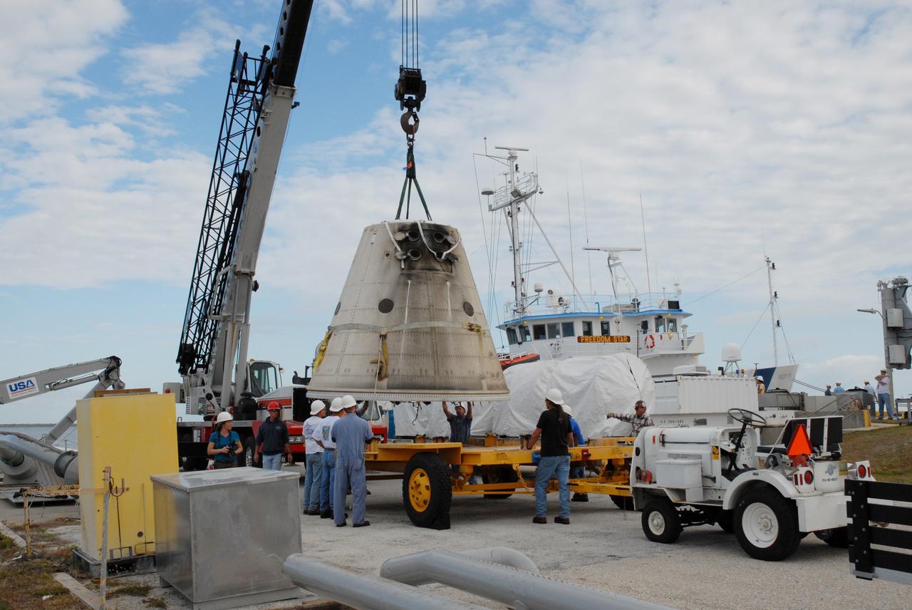 CAPE CANAVERAL, Fla. – At the dock at Hangar AF at Cape Canaveral Air Force Station in Florida, the frustum of a solid rocket booster is moved onto a transporter.  The booster was used during space shuttle Discovery's launch on mission STS-119 from NASA's Kennedy Space Center in Florida March 15.  The space shuttle’s solid rocket booster casings and associated flight hardware are recovered at sea after a launch. The spent rockets were recovered by NASA's Solid Rocket Booster Retrieval Ships Freedom Star and Liberty Star. The boosters impact the Atlantic Ocean approximately seven minutes after liftoff.  The splashdown area is a square of about six by nine nautical miles located about 140 nautical miles downrange from the launch pad. The retrieval ships are stationed approximately 8 to 10 nautical miles from the impact area at the time of splashdown. As soon as the boosters enter the water, the ships accelerate to a speed of 15 knots and quickly close on the boosters. The pilot chutes and main parachutes are the first items to be brought on board. With the chutes and frustum recovered, attention turns to the boosters. The ship’s tow line is connected and the booster is returned to the Port and, after transfer to a position alongside the ship, to Hangar AF. There, the expended boosters are disassembled, refurbished and reloaded with solid propellant for reuse.  Photo credit: NASA/Jack Pfaller