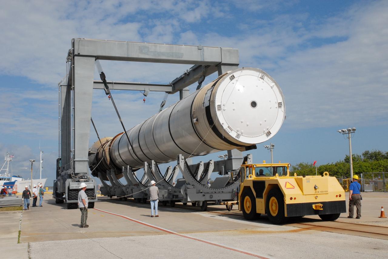 CAPE CANAVERAL, Fla. – At the dock at Hangar AF at Cape Canaveral Air Force Station in Florida, the straddle crane lowers a solid rocket booster onto a transporter. The booster was used during space shuttle Discovery's launch from NASA's Kennedy Space Center in Florida March 15 on mission STS-119. The space shuttle’s solid rocket booster casings and associated flight hardware are recovered at sea after a launch. The spent rockets were recovered by NASA's Solid Rocket Booster Retrieval Ships Freedom Star and Liberty Star. The boosters impact the Atlantic Ocean approximately seven minutes after liftoff.  The splashdown area is a square of about six by nine nautical miles located about 140 nautical miles downrange from the launch pad. The retrieval ships are stationed approximately 8 to 10 nautical miles from the impact area at the time of splashdown. As soon as the boosters enter the water, the ships accelerate to a speed of 15 knots and quickly close on the boosters. The pilot chutes and main parachutes are the first items to be brought on board. With the chutes and frustum recovered, attention turns to the boosters. The ship’s tow line is connected and the booster is returned to the Port and, after transfer to a position alongside the ship, to Hangar AF. There, the expended boosters are disassembled, refurbished and reloaded with solid propellant for reuse.  Photo credit: NASA/Jack Pfaller