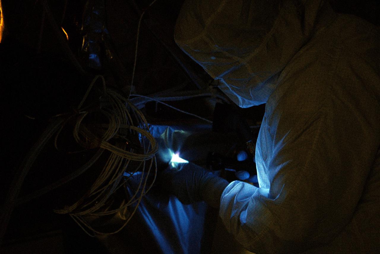 CAPE CANAVERAL, Fla. – At the Astrotech facility in Titusville, Fla., technicians perform backlight inspection and cleaning on NASA's Lunar Reconnaissance Orbiter, or LRO.  Black light inspection uses UVA fluorescence to detect possible particulate microcontamination, minute cracks or fluid leaks.  The orbiter will carry seven instruments to provide scientists with detailed maps of the lunar surface and enhance our understanding of the moon's topography, lighting conditions, mineralogical composition and natural resources. Information gleaned from LRO will be used to select safe landing sites, determine locations for future lunar outposts and help mitigate radiation dangers to astronauts. The polar regions of the moon are the main focus of the mission because continuous access to sunlight may be possible and water ice may exist in permanently shadowed areas of the poles. Accompanying LRO on its journey to the moon will be the Lunar CRater Observation and Sensing Satellite, or LCROSS, a mission that will impact the lunar surface in its search for water ice. Launch of LRO is targeted for May 20.  Photo credit: NASA/Kim Shiflett