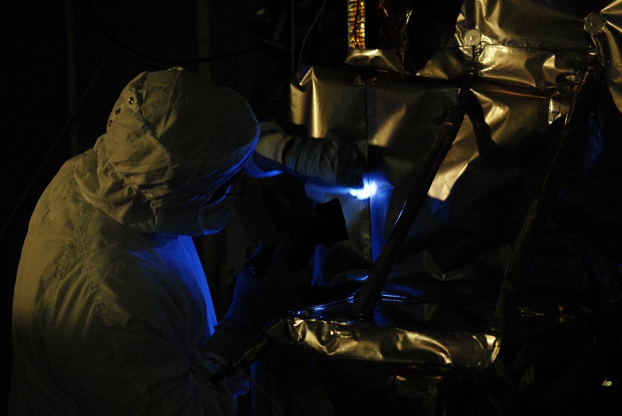 CAPE CANAVERAL, Fla. – At the Astrotech facility in Titusville, Fla., technicians perform backlight inspection and cleaning on NASA's Lunar Reconnaissance Orbiter, or LRO.  Black light inspection uses UVA fluorescence to detect possible particulate microcontamination, minute cracks or fluid leaks. The orbiter will carry seven instruments to provide scientists with detailed maps of the lunar surface and enhance our understanding of the moon's topography, lighting conditions, mineralogical composition and natural resources. Information gleaned from LRO will be used to select safe landing sites, determine locations for future lunar outposts and help mitigate radiation dangers to astronauts. The polar regions of the moon are the main focus of the mission because continuous access to sunlight may be possible and water ice may exist in permanently shadowed areas of the poles. Accompanying LRO on its journey to the moon will be the Lunar CRater Observation and Sensing Satellite, or LCROSS, a mission that will impact the lunar surface in its search for water ice. Launch of LRO is targeted for May 20.  Photo credit: NASA/Kim Shiflett