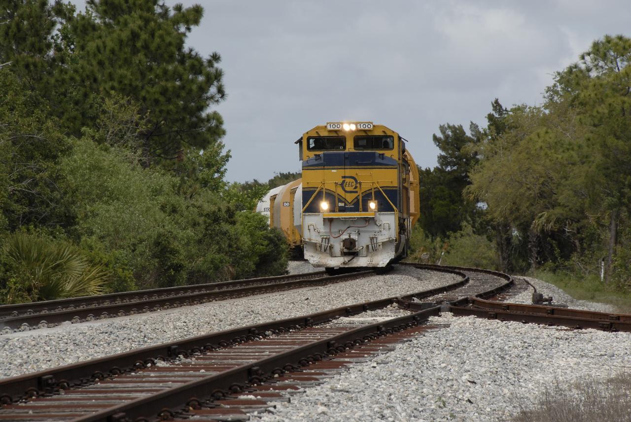 CAPE CANAVERAL, Fla. – The Florida East Coast Railway train arrives at the Jay Jay Rail Yard with the booster segments for the Ares I-X test rocket for interchange with the NASA Railroad. The four reusable motor segments and the nozzle exit cone, manufactured by the Ares I first-stage prime contractor Alliant Techsystems Inc., or ATK, departed Utah March 12 on the seven-day, cross-country trip to Florida.  The segments will be delivered to the  Rotation, Processing and Surge Facility for final processing and integration. The booster used for the Ares I-X launch is being modified by adding new forward structures and a fifth segment simulator. The motor is the final hardware needed for the rocket's upcoming test flight this summer. The stacking operations are scheduled to begin in the Vehicle Assembly Building in April.   Photo credit: NASA/Kim Shiflett
