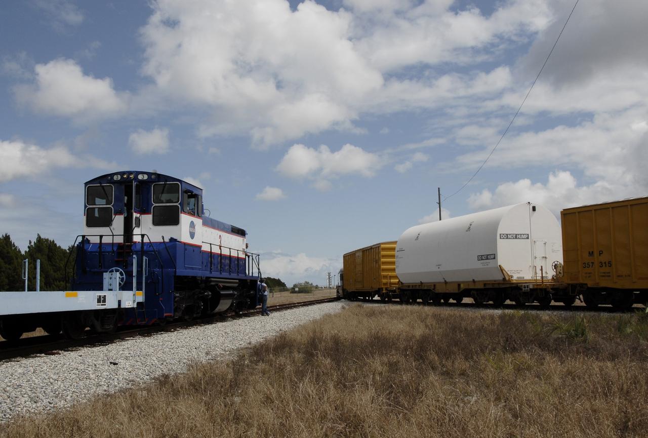 CAPE CANAVERAL, Fla. – The Florida East Coast Railway train arrives at the Jay Jay Rail Yard with the booster segments for the Ares I-X test rocket for interchange with the NASA Railroad. The four reusable motor segments and the nozzle exit cone, manufactured by the Ares I first-stage prime contractor Alliant Techsystems Inc., or ATK, departed Utah March 12 on the seven-day, cross-country trip to Florida.  The segments will be delivered to the  Rotation, Processing and Surge Facility for final processing and integration. The booster used for the Ares I-X launch is being modified by adding new forward structures and a fifth segment simulator. The motor is the final hardware needed for the rocket's upcoming test flight this summer. The stacking operations are scheduled to begin in the Vehicle Assembly Building in April.   Photo credit: NASA/Kim Shiflett