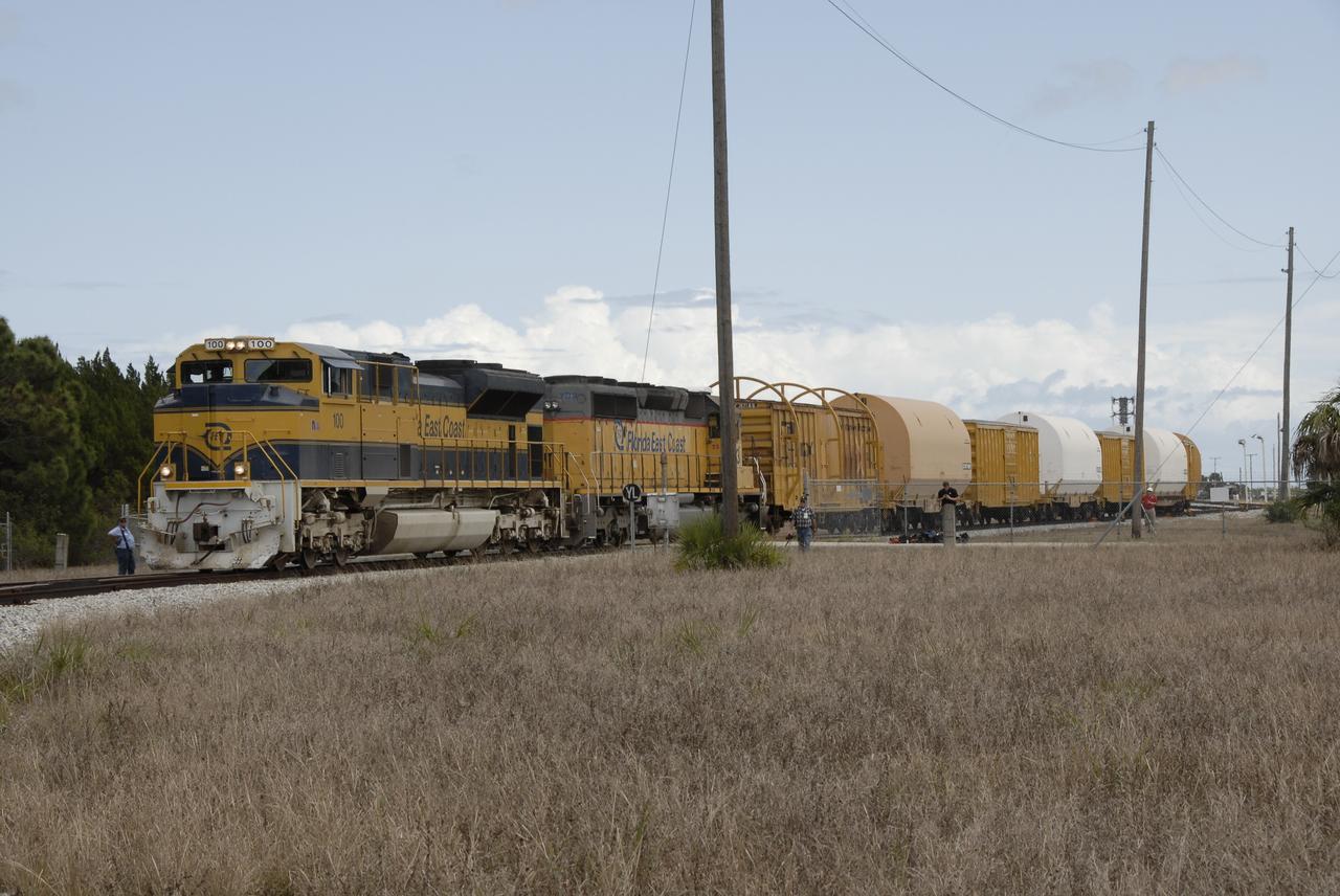 CAPE CANAVERAL, Fla. – The Florida East Coast Railway train arrives at the Jay Jay Rail Yard with the booster segments for the Ares I-X test rocket for interchange with the NASA Railroad.  The four reusable motor segments and the nozzle exit cone, manufactured by the Ares I first-stage prime contractor Alliant Techsystems Inc., or ATK, departed Utah March 12 on the seven-day, cross-country trip to Florida.  The segments will be delivered to the  Rotation, Processing and Surge Facility for final processing and integration. The booster used for the Ares I-X launch is being modified by adding new forward structures and a fifth segment simulator. The motor is the final hardware needed for the rocket's upcoming test flight this summer. The stacking operations are scheduled to begin in the Vehicle Assembly Building in April.   Photo credit: NASA/Kim Shiflett