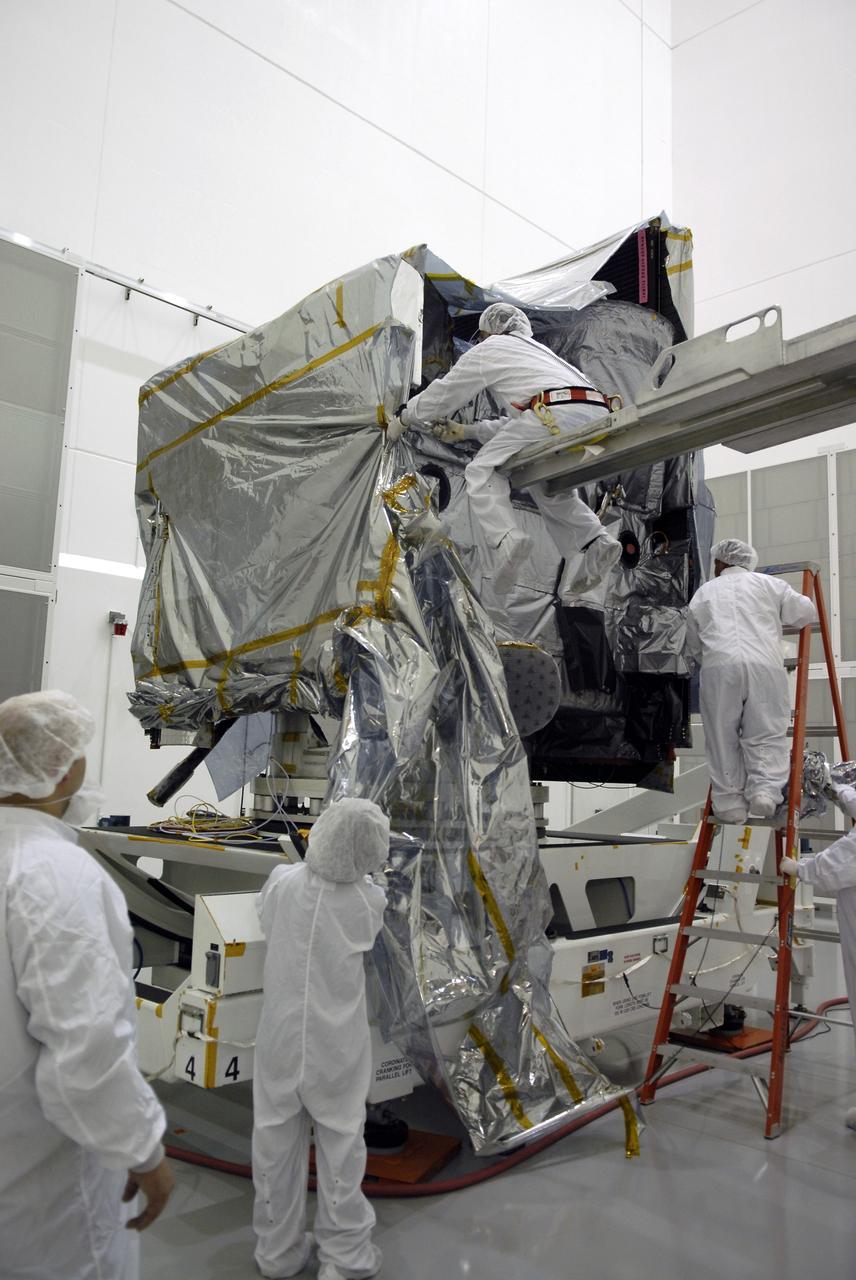 CAPE CANAVERAL, Fla. – At the Astrotech payload processing facility in Titusville, Fla., technicians remove the protective cover wrapped around the GOES-O satellite. The satellite will undergo final testing of the imaging system, instrumentation, communications and power systems. The latest Geostationary Operational Environmental Satellite, GOES-O was developed by NASA for the National Oceanic and Atmospheric Administration, or NOAA. The GOES-O satellite is targeted to launch April 28 onboard a United Launch Alliance Delta IV expendable launch vehicle. Once in orbit, GOES-O will be designated GOES-14, and NASA will provide on-orbit checkout and then transfer operational responsibility to NOAA. GOES-O will be placed in on-orbit storage as a replacement for an older GOES satellite. GOES-O carries an advanced attitude control system using star trackers with spacecraft optical bench Imager and Sounder mountings that provide enhanced instrument pointing performance for improved image navigation and registration to better locate severe storms and other events important to the NOAA National Weather Service. Photo credit: NASA/Kim Shiflett