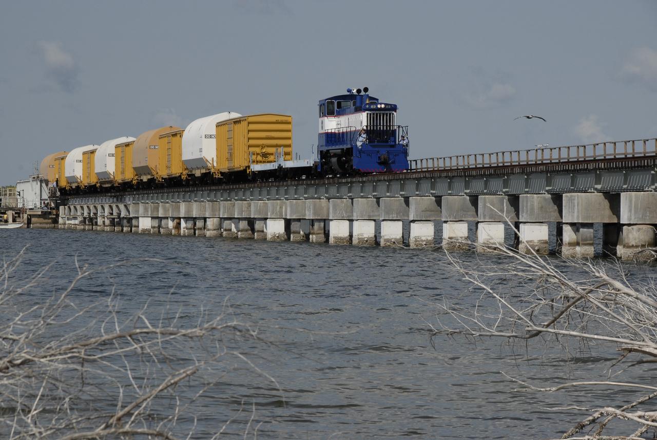CAPE CANAVERAL, Fla. – The NASA Railroad hauls cars carrying the Ares I-X motor segments and nozzle exit cone over a river bridge to NASA's Kennedy Space Center in Florida.  The four reusable motor segments and the nozzle exit cone, manufactured by the Ares I first-stage prime contractor Alliant Techsystems Inc., or ATK, departed Utah March 12 on the seven-day, cross-country trip to Florida.  The segments will be delivered to Kennedy's  Rotation, Processing and Surge Facility for final processing and integration. The booster used for the Ares I-X launch is being modified by adding new forward structures and a fifth segment simulator. The motor is the final hardware needed for the rocket's upcoming test flight this summer. The stacking operations are scheduled to begin in the Vehicle Assembly Building in April.   Photo credit: NASA/Kim Shiflett