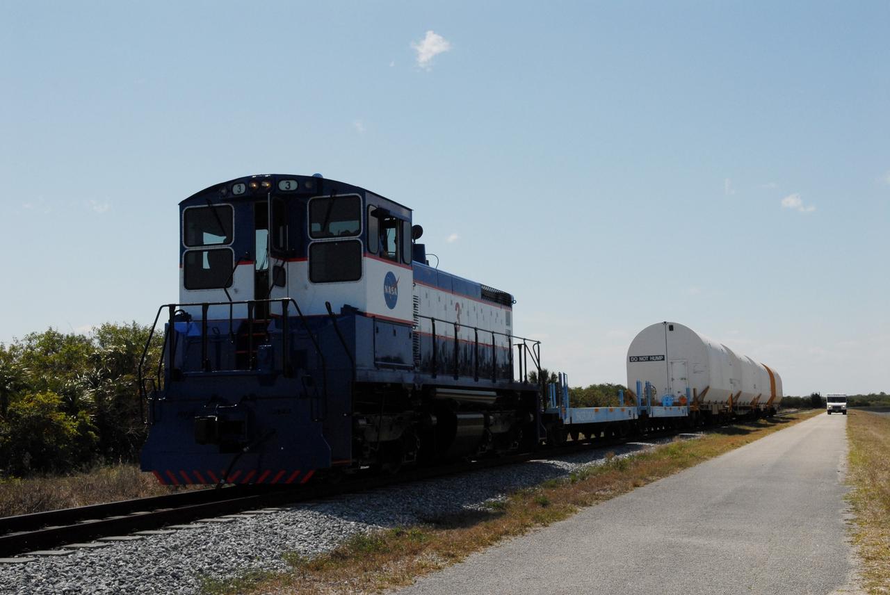 CAPE CANAVERAL, Fla. – After switching out the box cars on the train, the NASA Railroad hauls the Ares I-X motor segments and nozzle exit cone to NASA's Kennedy Space Center in Florida. The four reusable motor segments and the nozzle exit cone, manufactured by the Ares I first-stage prime contractor Alliant Techsystems Inc., or ATK, departed Utah March 12 on the seven-day, cross-country trip to Florida.  The segments will be delivered to Kennedy's  Rotation, Processing and Surge Facility for final processing and integration. The booster used for the Ares I-X launch is being modified by adding new forward structures and a fifth segment simulator. The motor is the final hardware needed for the rocket's upcoming test flight this summer. The stacking operations are scheduled to begin in the Vehicle Assembly Building in April.   Photo credit: NASA/Jack Pfaller