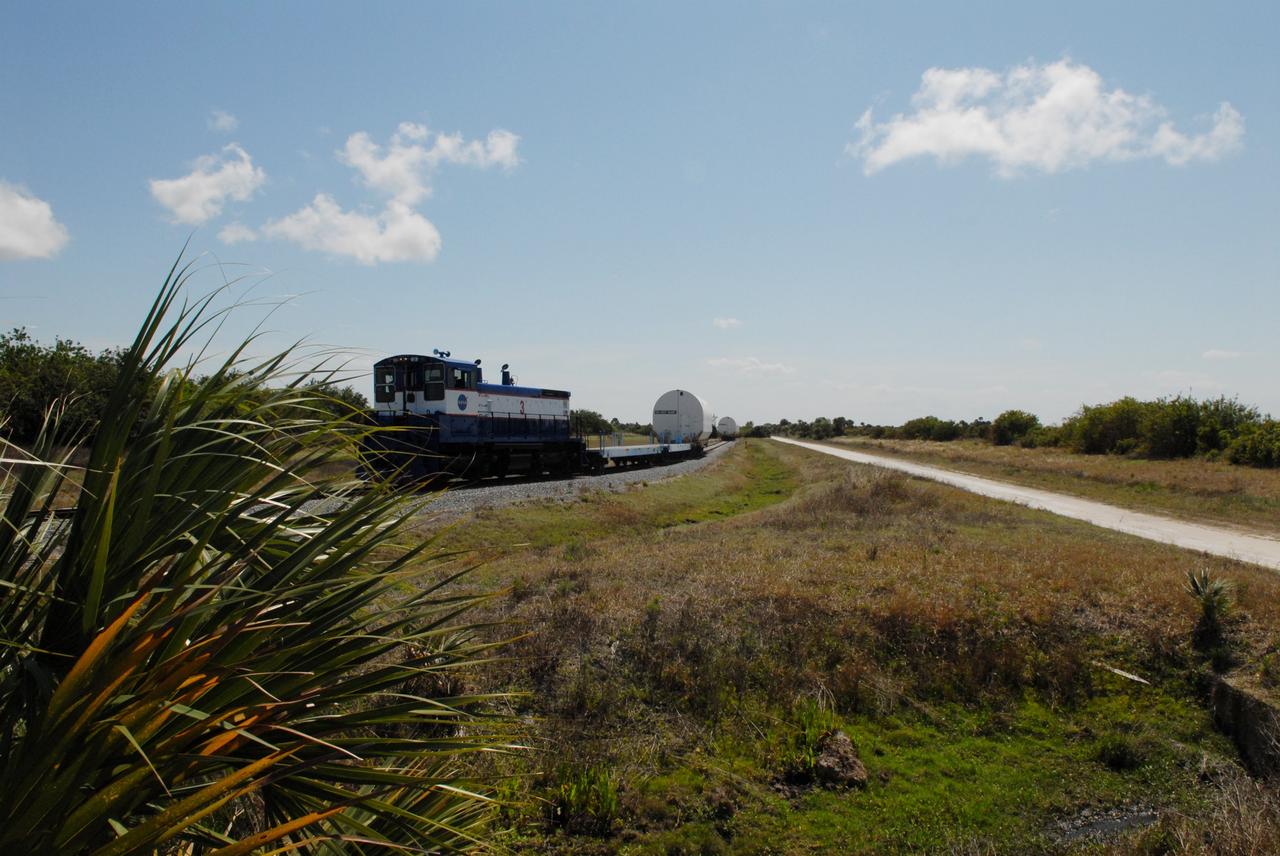 CAPE CANAVERAL, Fla. – The NASA Railroad leaves four of the cars with Ares I-X segments at Suspect siding on NASA's Kennedy Space Center in Florida and continues on with the remaining car to the Rotation, Processing and Surge Facility.  The four reusable motor segments and the nozzle exit cone, manufactured by the Ares I first-stage prime contractor Alliant Techsystems Inc., or ATK, departed Utah March 12 on the seven-day, cross-country trip to Florida.  The segments will be delivered to Kennedy's  Rotation, Processing and Surge Facility for final processing and integration. The booster used for the Ares I-X launch is being modified by adding new forward structures and a fifth segment simulator. The motor is the final hardware needed for the rocket's upcoming test flight this summer. The stacking operations are scheduled to begin in the Vehicle Assembly Building in April.   Photo credit: NASA/Jack Pfaller
