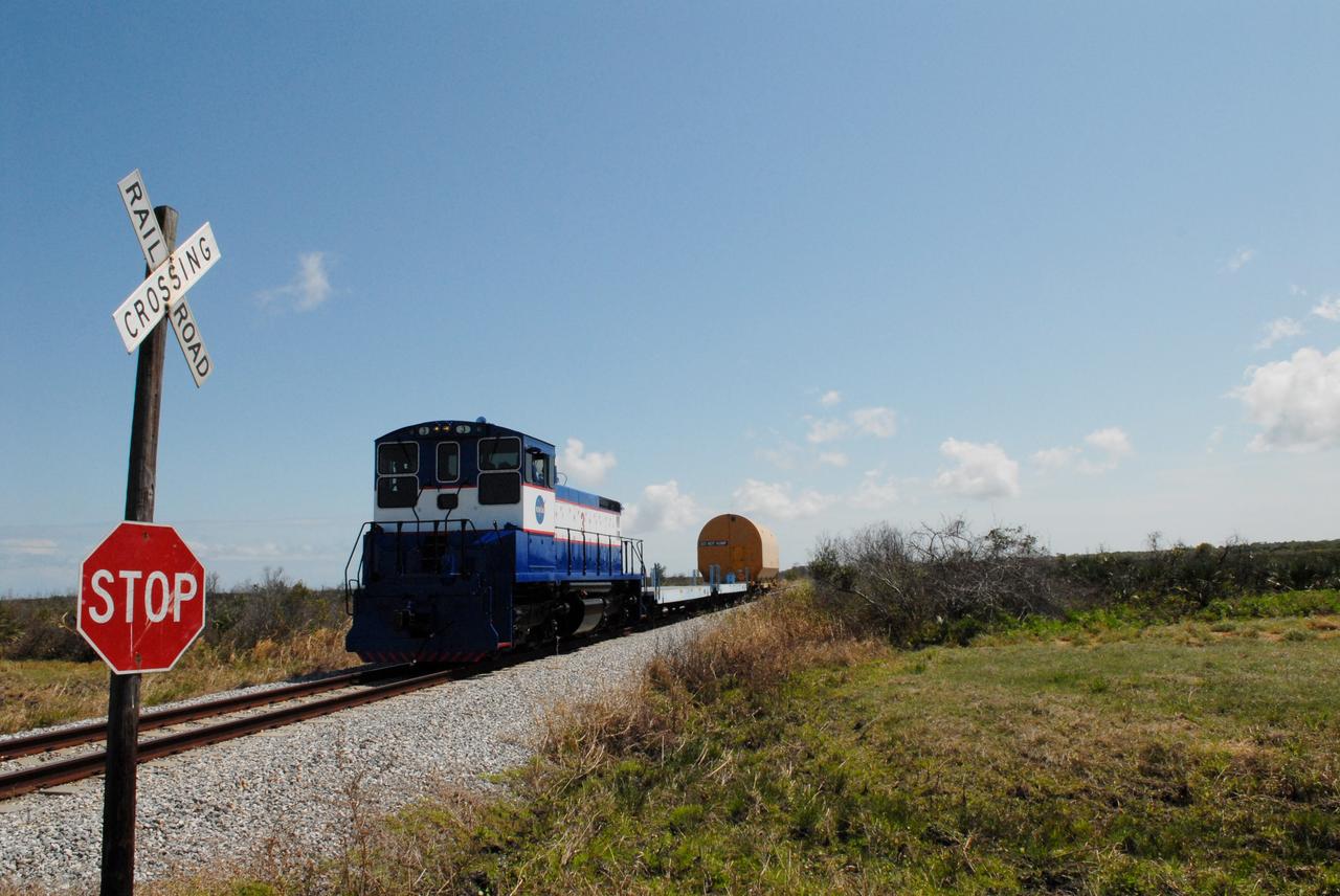 CAPE CANAVERAL, Fla. –This NASA Railroad engine is hauling one of the cars with an Ares I-X segment to the Rotation, Processing and Surge Facility at NASA's Kennedy Space Center in Florida.  The four reusable motor segments and the nozzle exit cone, manufactured by the Ares I first-stage prime contractor Alliant Techsystems Inc., or ATK, departed Utah March 12 on the seven-day, cross-country trip to Florida.  The segments will be delivered to Kennedy's  Rotation, Processing and Surge Facility for final processing and integration. The booster used for the Ares I-X launch is being modified by adding new forward structures and a fifth segment simulator. The motor is the final hardware needed for the rocket's upcoming test flight this summer. The stacking operations are scheduled to begin in the Vehicle Assembly Building in April.   Photo credit: NASA/Jack Pfaller