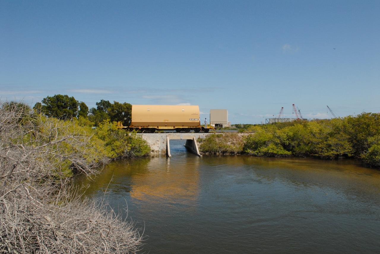 CAPE CANAVERAL, Fla. –The NASA Railroad is hauling one of the cars with an Ares I-X segment to the Rotation, Processing and Surge Facility at NASA's Kennedy Space Center in Florida.  The four reusable motor segments and the nozzle exit cone, manufactured by the Ares I first-stage prime contractor Alliant Techsystems Inc., or ATK, departed Utah March 12 on the seven-day, cross-country trip to Florida.  The segments will be delivered to Kennedy's  Rotation, Processing and Surge Facility for final processing and integration. The booster used for the Ares I-X launch is being modified by adding new forward structures and a fifth segment simulator. The motor is the final hardware needed for the rocket's upcoming test flight this summer. The stacking operations are scheduled to begin in the Vehicle Assembly Building in April.   Photo credit: NASA/Jack Pfaller