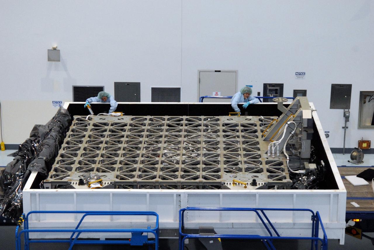 CAPE CANAVERAL, Fla. – Inside the Space Station Processing Facility at NASA's Kennedy Space Center in Florida, technicians check the EXPRESS Logistics Carrier for the STS-129 mission after its cover was removed. The carrier is part of the payload on space shuttle Atlantis, which will deliver to the International Space Station components including two spare gyroscopes, two nitrogen tank assemblies, two pump modules, an ammonia tank assembly and a spare latching end effector for the station's robotic arm. STS-129 is targeted to launch Nov. 12. Photo credit: NASA/Tim Jacobs