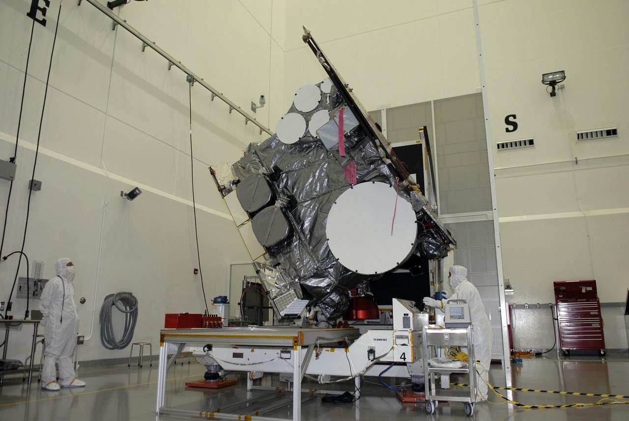 CAPE CANAVERAL, Fla. – At the Astrotech payload processing facility in Titusville, Fla., technicians examine the progress of the GOES-O satellite as it rotates on the stand. The latest Geostationary Operational Environmental Satellite, GOES-O was developed by NASA for the National Oceanic and Atmospheric Administration, or NOAA. Once in orbit, GOES-O will be designated GOES-14, and NASA will provide on-orbit checkout and then transfer operational responsibility to NOAA. The GOES-O satellite is targeted to launch April 28 onboard a United Launch Alliance Delta IV expendable launch vehicle.  Photo credit: NASA/Kim Shiflett