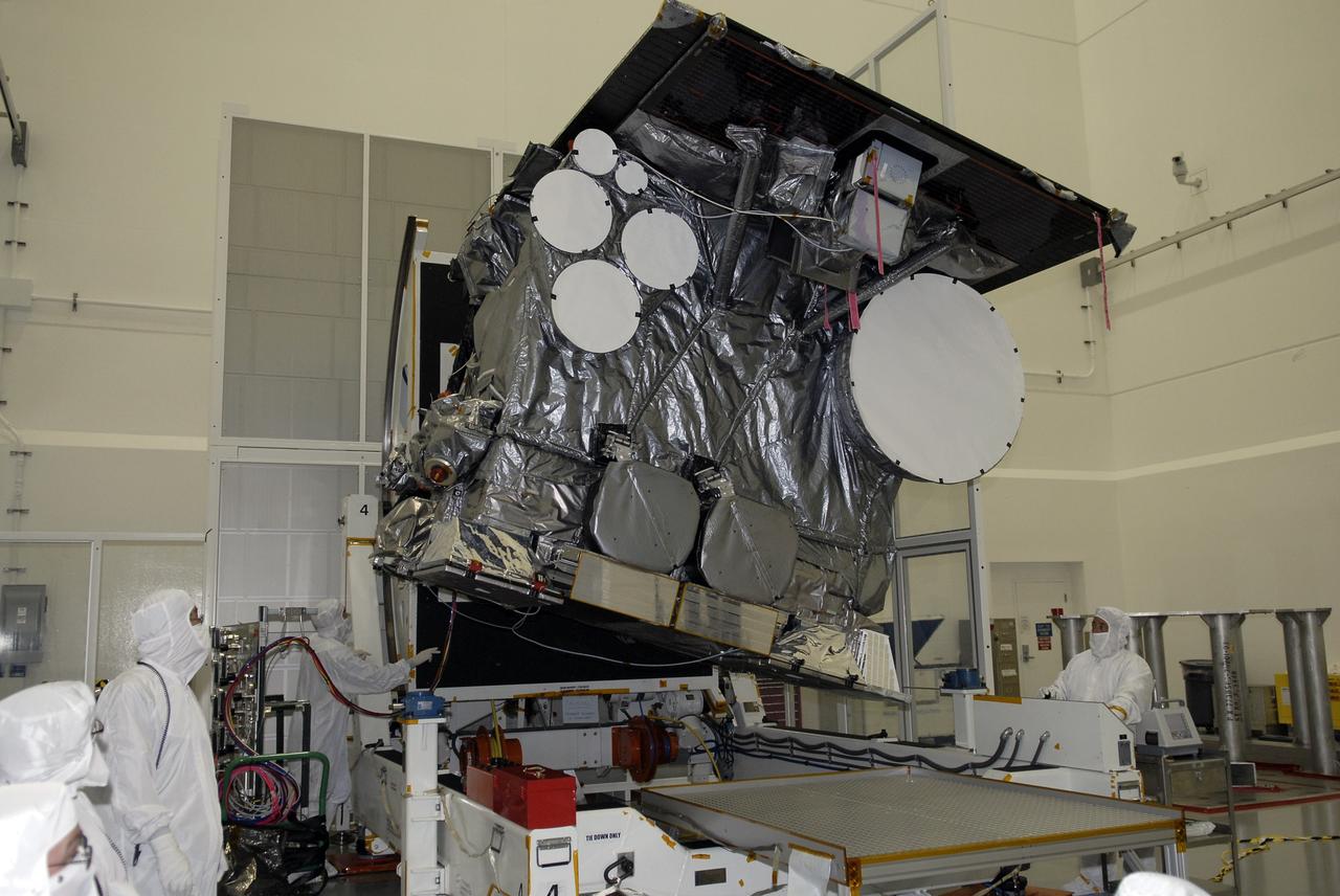 CAPE CANAVERAL, Fla. – At the Astrotech payload processing facility in Titusville, Fla., technicians at right and left examine the GOES-O satellite as it rotates on the stand. The latest Geostationary Operational Environmental Satellite, GOES-O was developed by NASA for the National Oceanic and Atmospheric Administration, or NOAA. Once in orbit, GOES-O will be designated GOES-14, and NASA will provide on-orbit checkout and then transfer operational responsibility to NOAA. The GOES-O satellite is targeted to launch April 28 onboard a United Launch Alliance Delta IV expendable launch vehicle.  Photo credit: NASA/Kim Shiflett