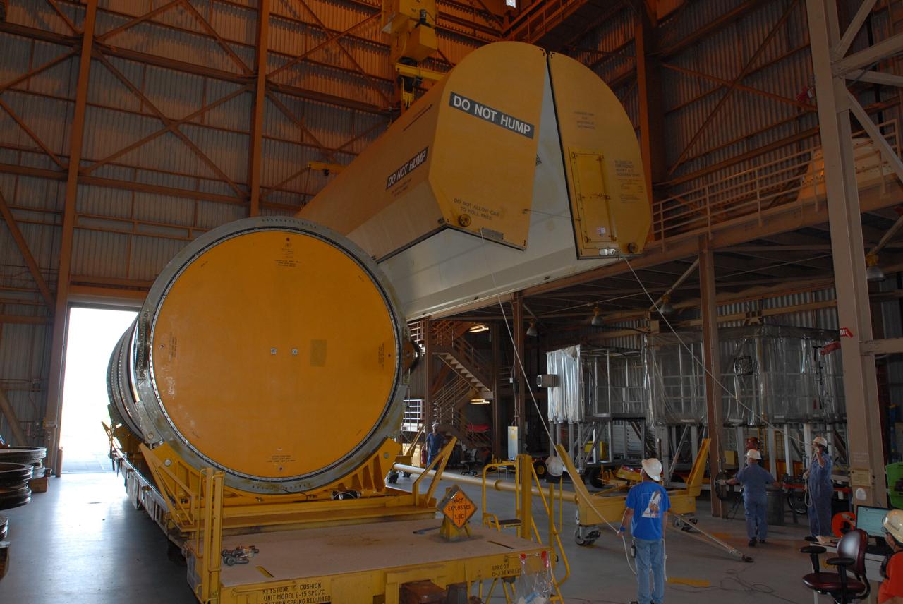 CAPE CANAVERAL, Fla. – In the Rotation, Processing and Surge Facility at NASA's Kennedy Space Center in Florida, the rail car cover is moved away from the first Ares I-X motor segment. It is one of four reusable motor segments and nozzle exit cone shipped by the Ares I first-stage prime contractor Alliant Techsystems Inc. for final processing and integration in the facility. The booster used for the Ares I-X launch is being modified by adding new forward structures and a fifth segment simulator. The motor is the final hardware needed for the rocket's upcoming flight test this summer. The stacking operations are scheduled to begin in the Vehicle Assembly Building in April. Photo credit: NASA/Jim Grossmann