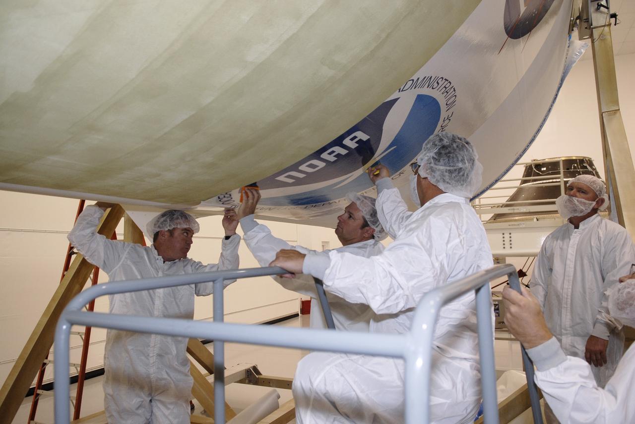 CAPE CANAVERAL, Fla. –  At the Astrotech payload processing facility in Titusville, Fla., technicians apply the NOAA decal to the fairing that will encapsulate the GOES-O satellite during launch.  The latest Geostationary Operational Environmental Satellite, GOES-O was developed by NASA for the National Oceanic and Atmospheric Administration, or NOAA. The GOES satellites continuously provide observations of 60 percent of the Earth including the continental United States, providing weather monitoring and forecast operations as well as a continuous and reliable stream of environmental information and severe weather warnings. Once in orbit, GOES-O will be designated GOES-14, and NASA will provide on-orbit checkout and then transfer operational responsibility to NOAA. The GOES-O satellite is targeted to launch April 28 onboard a United Launch Alliance Delta IV expendable launch vehicle. Photo credit: NASA/Kim Shiflett