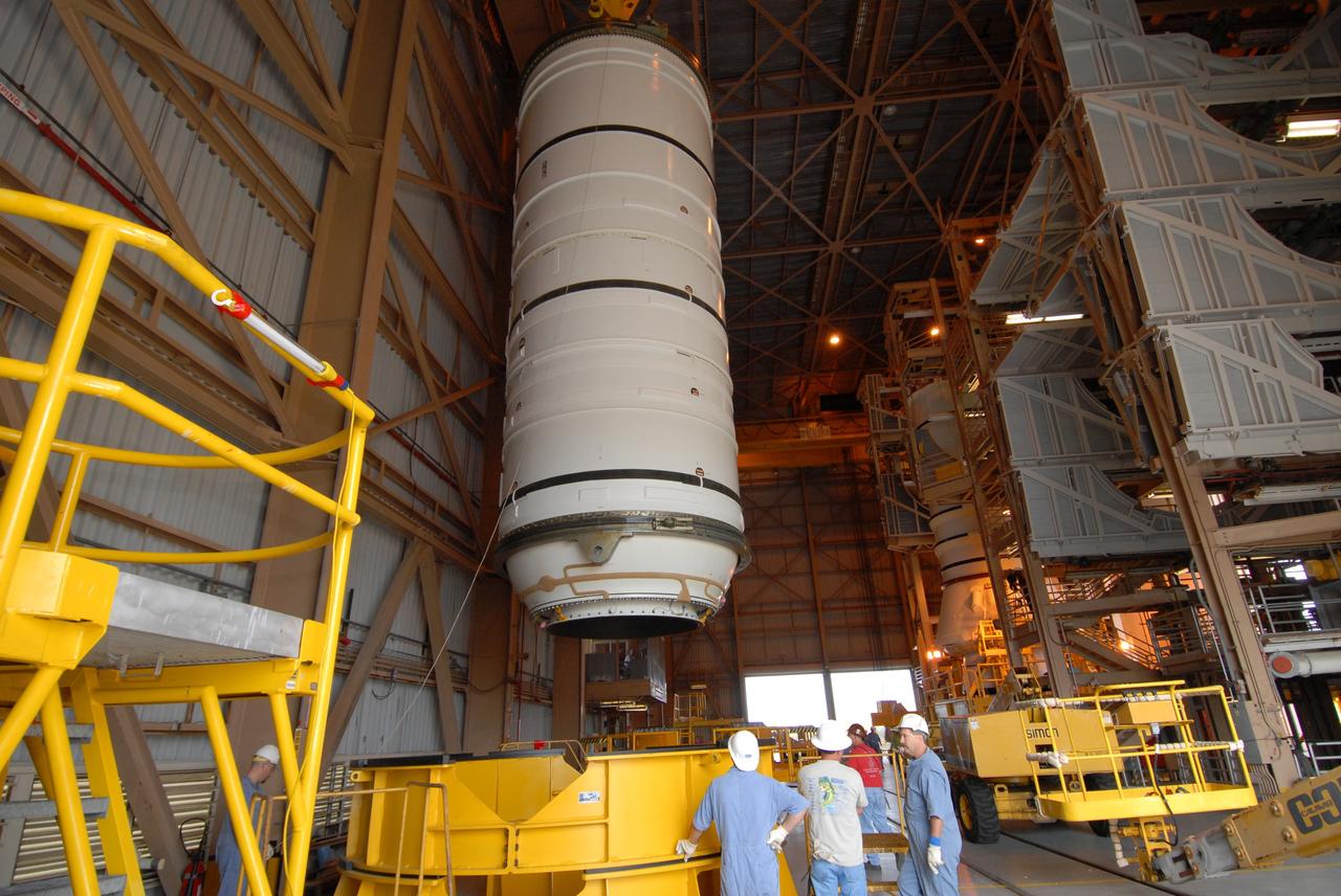 CAPE CANAVERAL, Fla. –  Technicians stand by as the Ares I-X motor segment is moved toward a work stand in the Rotation, Processing and Surge Facility at NASA's Kennedy Space Center in Florida. Four segments were delivered to Kennedy for final processing and integration. The booster used for the Ares I-X launch is being modified by adding new forward structures and a fifth segment simulator. The motor is the final hardware needed for the rocket's upcoming test flight this summer. The stacking operations are scheduled to begin in the Vehicle Assembly Building in April.  Photo credit: NASA/Jack Pfaller