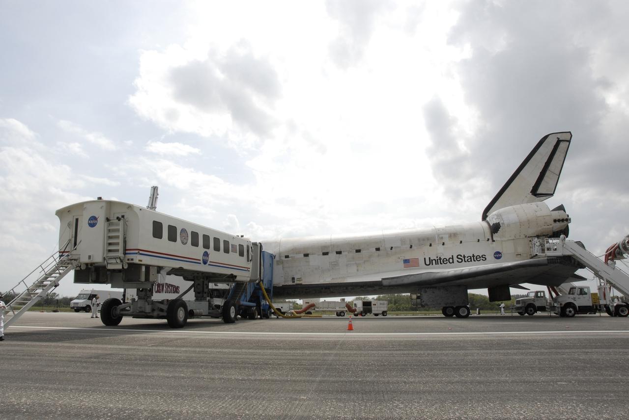 CAPE CANAVERAL, Fla. – The crew transport vehicle is positioned against space shuttle Discovery on Runway 15 at NASA's Kennedy Space Center in Florida following touchdown to complete the 13-day, 5.3-million mile journey on the STS-119 mission to the International Space Station. Main gear touchdown was at 3:13:17 p.m. EDT.  Nose gear touchdown was at 3:13:40 p.m. and wheels stop was at 3:14:45 p.m.  Discovery delivered the final pair of large power-generating solar array wings and the S6 truss segment. The mission was the 28th flight to the station, the 36th flight of Discovery and the 125th in the Space Shuttle Program, as well as the 70th landing at Kennedy. Photo credit: NASA/Kim Shiflett
