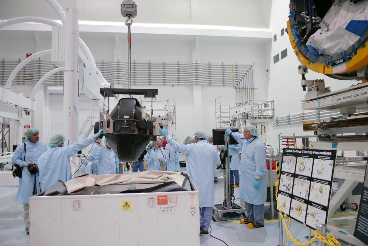 CAPE CANAVERAL, Fla. – In the Space Station Processing Facility at NASA's Kennedy Space Center in Florida, technicians help guide the control moment gyro, or CMG, as a crane lifts and moves it from its container.  The CMG is part of the payload on the STS-129 mission to the International Space Station. On the mission, space shuttle Atlantis also will deliver the orbital spares and replacement parts to sustain the life of the station.  Photo credit: NASA/Troy Cryder