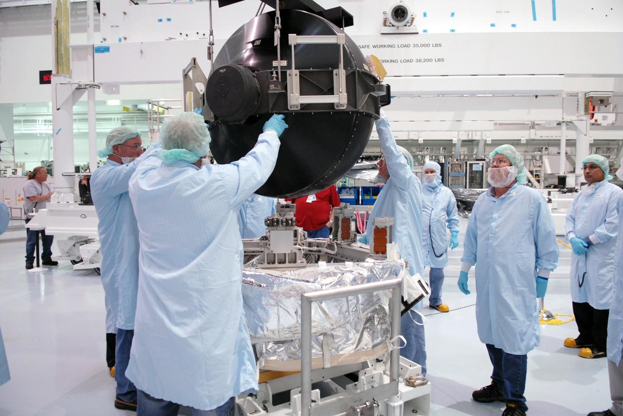 CAPE CANAVERAL, Fla. – In the Space Station Processing Facility at NASA's Kennedy Space Center in Florida, technicians help guide the control moment gyroscope, or CMG, toward the small adapter plate assembly below.  The CMG is part of the payload on the STS-129 mission to the International Space Station. On the mission, space shuttle Atlantis also will deliver the orbital spares and replacement parts to sustain the life of the station.  Photo credit: NASA/Troy Cryder