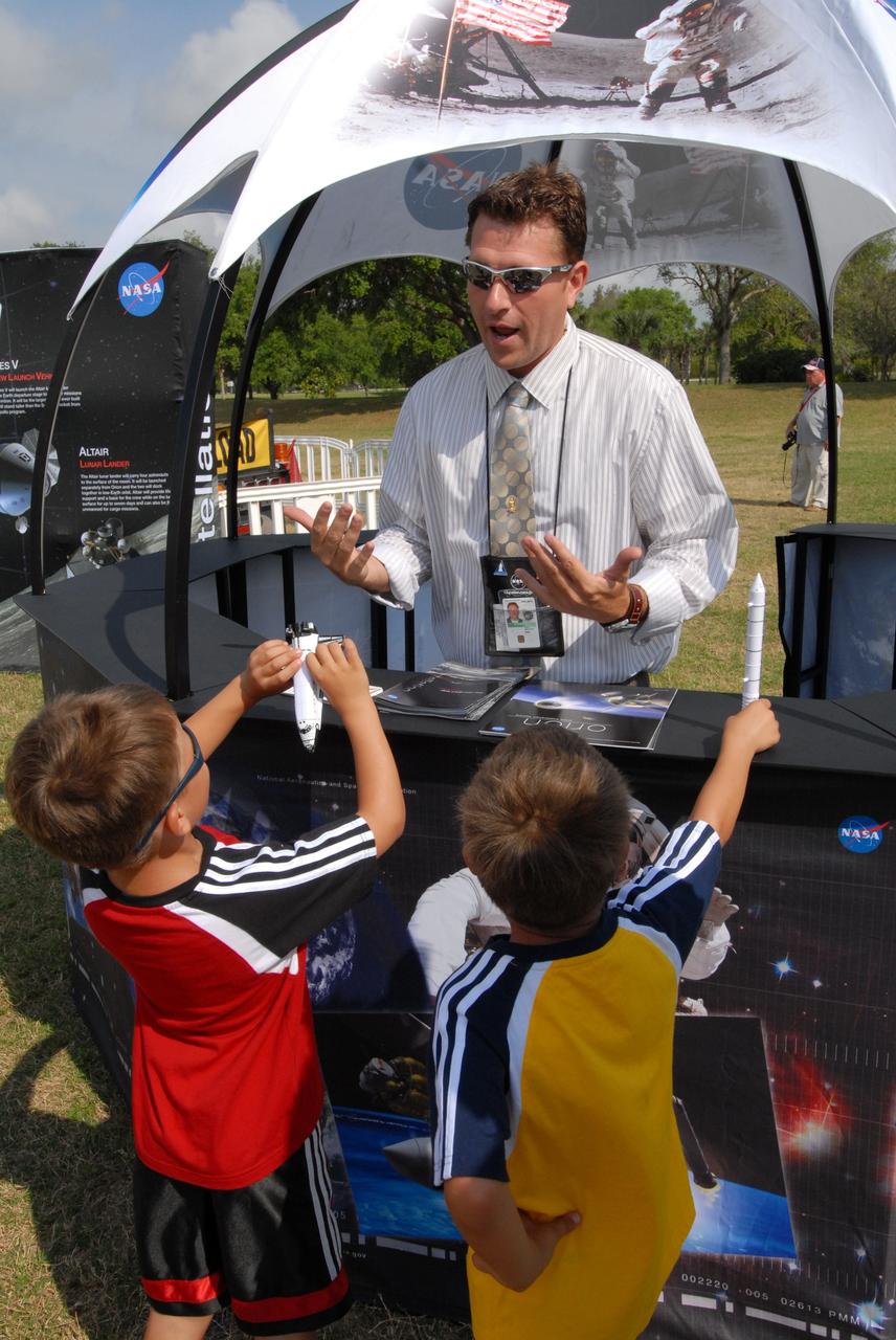 CAPE CANAVERAL, Fla. –  A NASA official talks to visitors at the Kennedy Space Center Visitor Complex in Florida about the Orion crew exploration vehicle mockup and the Constellation Program. The Orion mockup is on display before heading offshore to be tested in open water. The spacecraft mock-up traveled from the Naval Surface Warfare Center's Carderock Division in Bethesda, Md. The goal of the open water testing, dubbed the Post-landing Orion Recovery Test, or PORT, is to determine what kind of motion astronauts can expect after landing, as well as outside conditions for recovery teams. Part of the Constellation Program, Orion is targeted to begin carrying humans to the International Space Station in 2015 and to the moon by 2020.   Photo credit: NASA/Jack Pfaller