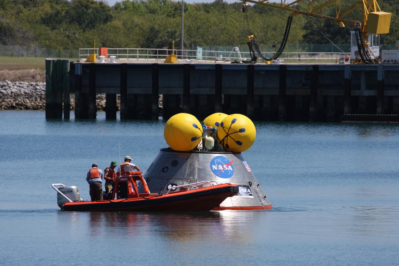 CAPE CANAVERAL, Fla. – Members of the 920th Rescue Wing get ready to release a flotation collar around the mockup Orion crew exploration vehicle at the Trident Basin at Port Canaveral, Fla.  On top of Orion are additional flotation devices. The goal of the operation, dubbed the Post-landing Orion Recovery Test, or PORT, is to determine what kind of motion astronauts can expect after landing, as well as outside conditions for recovery teams.  Orion is targeted to begin carrying humans to the International Space Station in 2015 and to the moon by 2020.  Orion, along with the Ares I and V rockets and the Altair lunar lander, are part of the Constellation Program.  Photo credit: NASA/Dimitri Gerondidakis