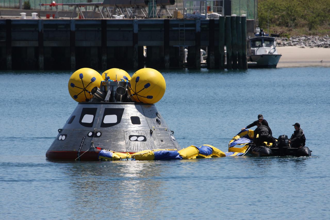 CAPE CANAVERAL, Fla. – Members of the 920th Rescue Wing release a flotation collar around the mockup Orion crew exploration vehicle at the Trident Basin at Port Canaveral, Fla.  On top of Orion are additional flotation devices. The goal of the operation, dubbed the Post-landing Orion Recovery Test, or PORT, is to determine what kind of motion astronauts can expect after landing, as well as outside conditions for recovery teams.  Orion is targeted to begin carrying humans to the International Space Station in 2015 and to the moon by 2020.  Orion is targeted to begin carrying humans to the International Space Station in 2015 and to the moon by 2020.  Orion, along with the Ares I and V rockets and the Altair lunar lander, are part of the Constellation Program.  Photo credit: NASA/Dimitri Gerondidakis