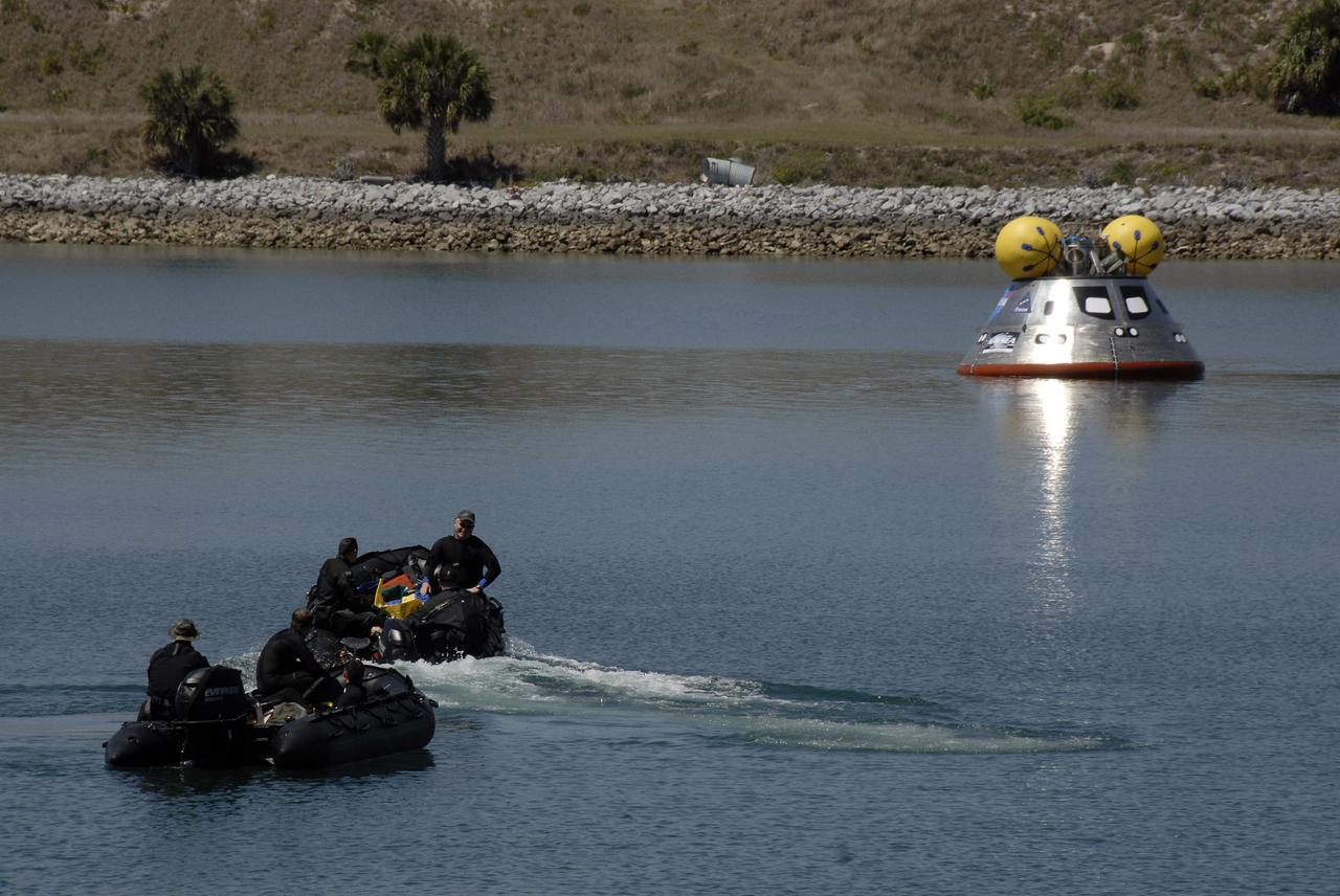 CAPE CANAVERAL, Fla. – Members of the 920th Rescue Wing make their way toward the mockup Orion crew exploration vehicle floating in the open water of the Trident Basin at Port Canaveral, Fla.  They will place a flotation collar around the mockup vehicle. The mockup vehicle will undergo testing in open water. The goal of the operation, dubbed the Post-landing Orion Recovery Test, or PORT, is to determine what kind of motion astronauts can expect after landing, as well as outside conditions for recovery teams. Orion is targeted to begin carrying humans to the International Space Station in 2015 and to the moon by 2020.  Orion, along with the Ares I and V rockets and the Altair lunar lander, are part of the Constellation Program.  Photo credit: NASA/Kim Shiflett
