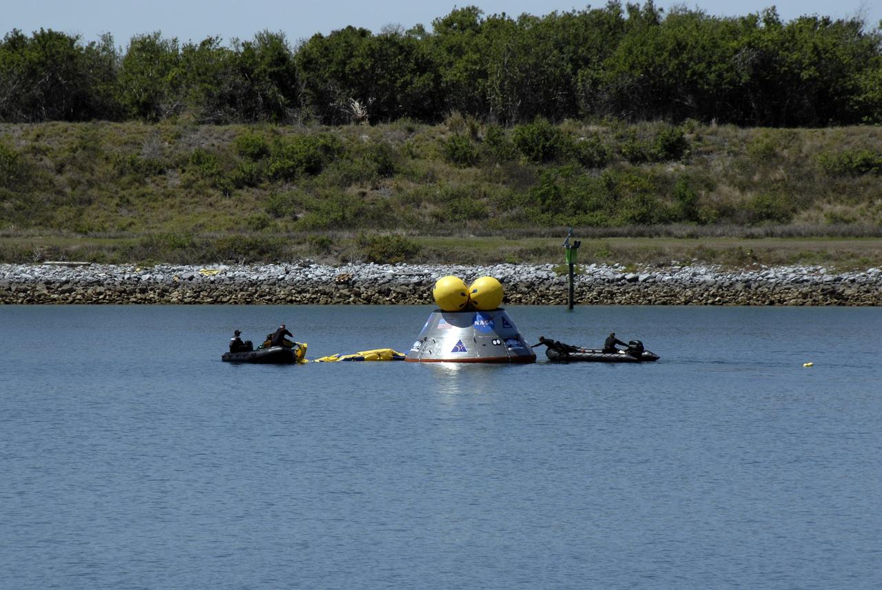 CAPE CANAVERAL, Fla. – Members of the 920th Rescue Wing release a flotation collar around the mockup Orion crew exploration vehicle at the Trident Basin at Port Canaveral, Fla.  On top of Orion are additional flotation devices. The mockup vehicle will undergo testing in open water. The goal of the operation, dubbed the Post-landing Orion Recovery Test, or PORT, is to determine what kind of motion astronauts can expect after landing, as well as outside conditions for recovery teams.  Orion is targeted to begin carrying humans to the International Space Station in 2015 and to the moon by 2020. Orion, along with the Ares I and V rockets and the Altair lunar lander, are part of the Constellation Program.  Photo credit: NASA/Kim Shiflett
