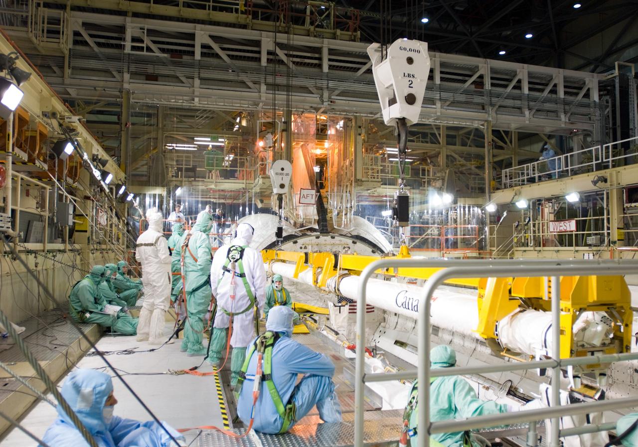 CAPE CANAVERAL, Fla. – In the Orbiter Processing Facility’s bay 3, workers install the orbiter boom sensor system in the payload bay of space shuttle Discovery to support mission STS-128. The 50-foot-long boom attaches to the shuttle arm and provides equipment to inspect the shuttle's heat shield while in space. It contains an intensified television camera (ITVC) and a laser dynamic range imager, which are mounted on a pan and tilt unit, and a laser camera system (LCS) mounted on a stationary bracket.  The STS-128 flight will carry science and storage racks to the International Space Station on space shuttle Discovery. Launch of Discovery is targeted for Aug. 6. Photo credit: NASA/Jim Grossmann