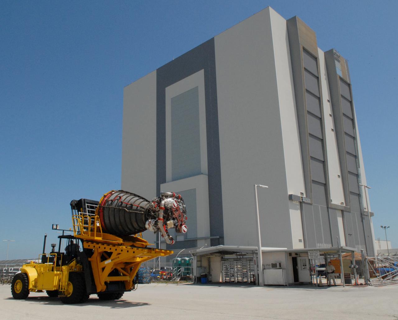 CAPE CANAVERAL, Fla. – After removal from space shuttle Discovery, the third and final main engine has left Orbiter Processing Facility 3 at NASA's Kennedy Space Center in Florida.  Behind the Hyster forklift holding the engine is the Vehicle Assembly Building. Each engine is 14 feet long, weighs about 6,700 pounds, and is 7.5 feet in diameter at the end of the nozzle. Discovery next will be used on the STS-128 mission to deliver supplies and equipment to the International Space Station.  The launch is targeted for Aug. 6.  Photo credit: NASA/Tim Jacobs